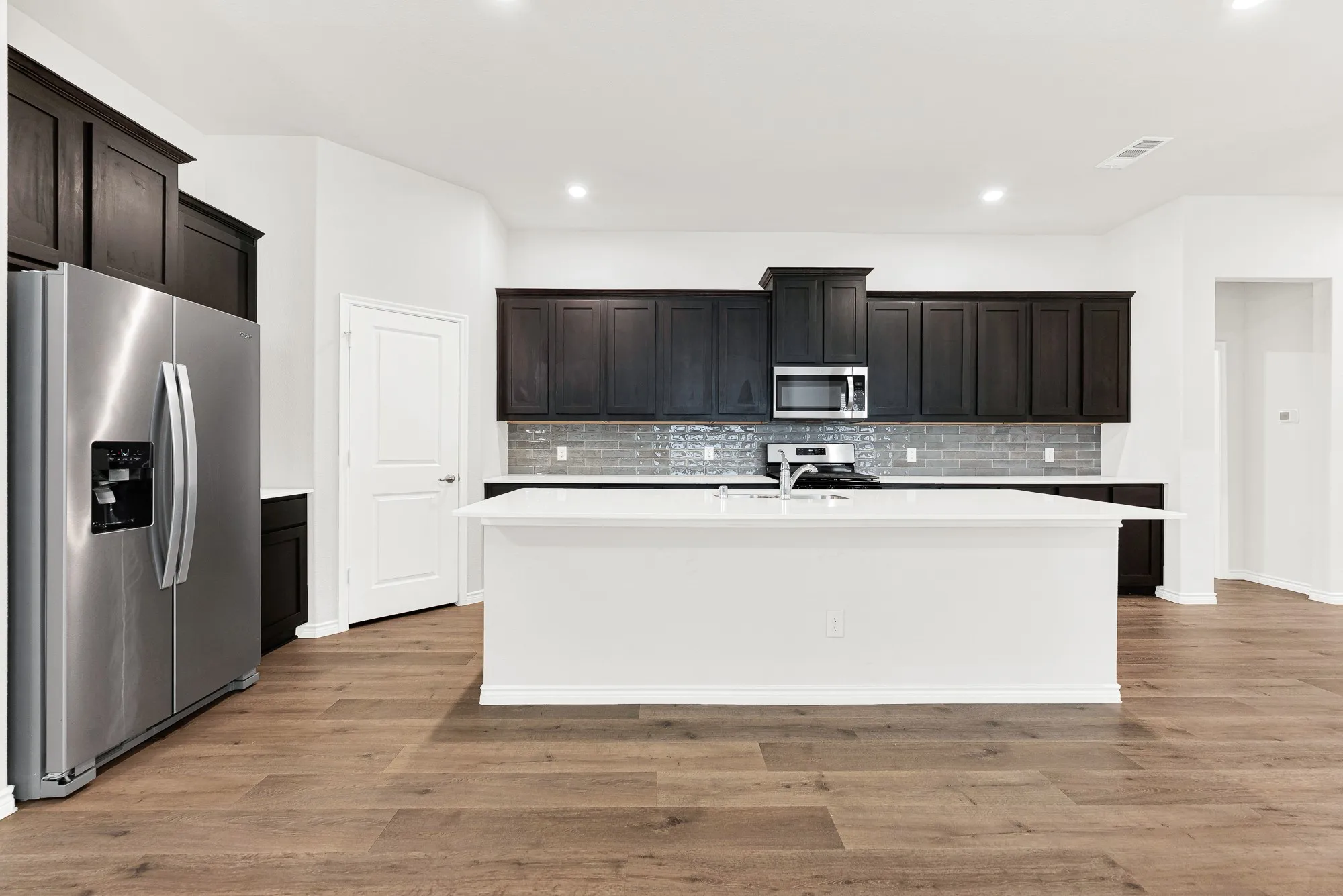 From this straight-on angle, the kitchen's wide, functional layout is clear, anchored by the oversized central island. It's the perfect central hub for casual morning breakfasts, setting out party appetizers, or just hanging out.