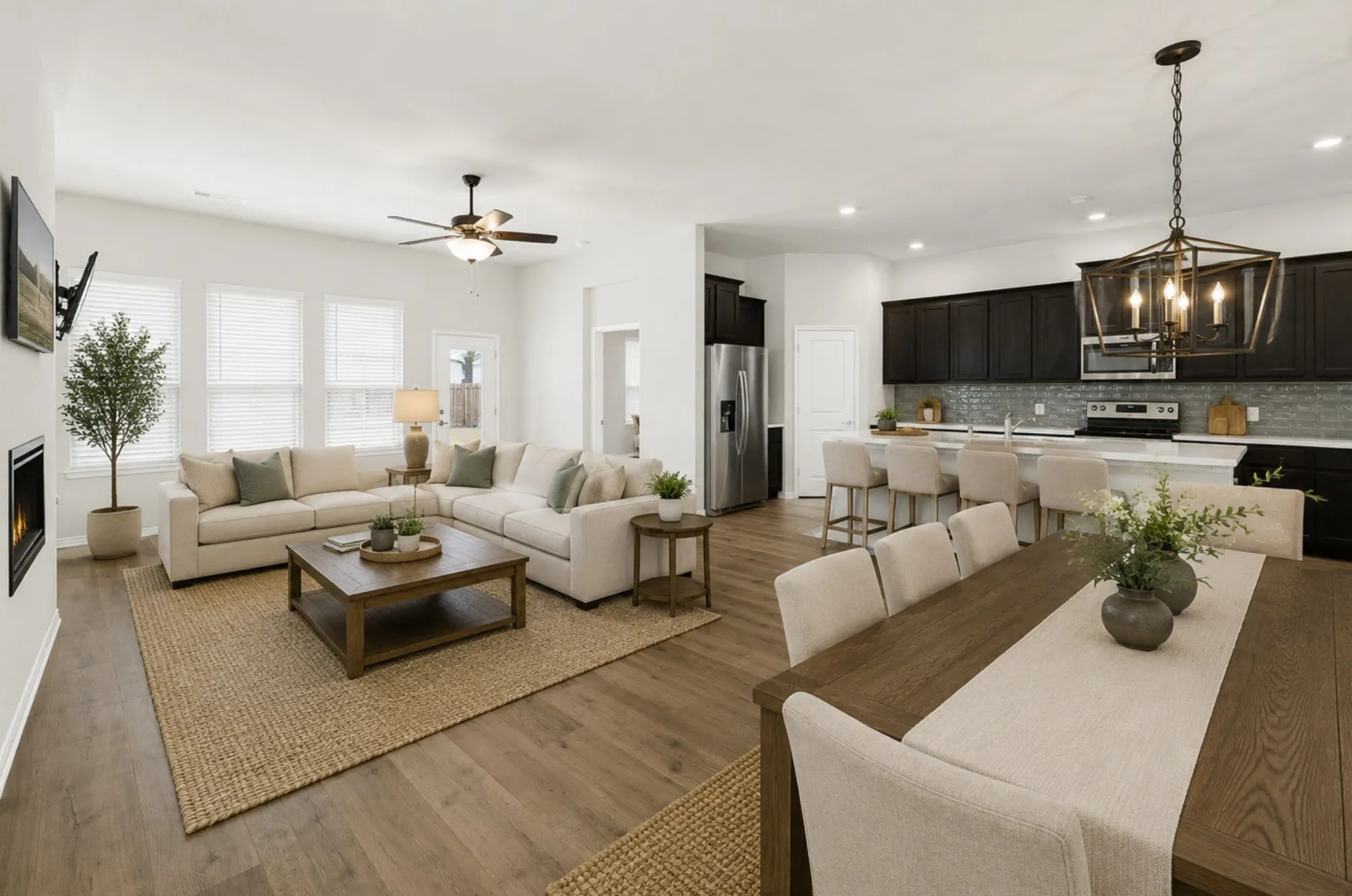 Looking back towards the heart of the home, this angle showcases the dining area’s placement within the grand great room, framed by the modern kitchen with its sophisticated dark cabinetry, sleek subway tile backsplash, and spacious island. The integrated ceiling fan and recessed lighting create a comfortable atmosphere for everyday family meals or celebrating special occasions with a smooth transition to after-dinner relaxation. *Virtually Staged*