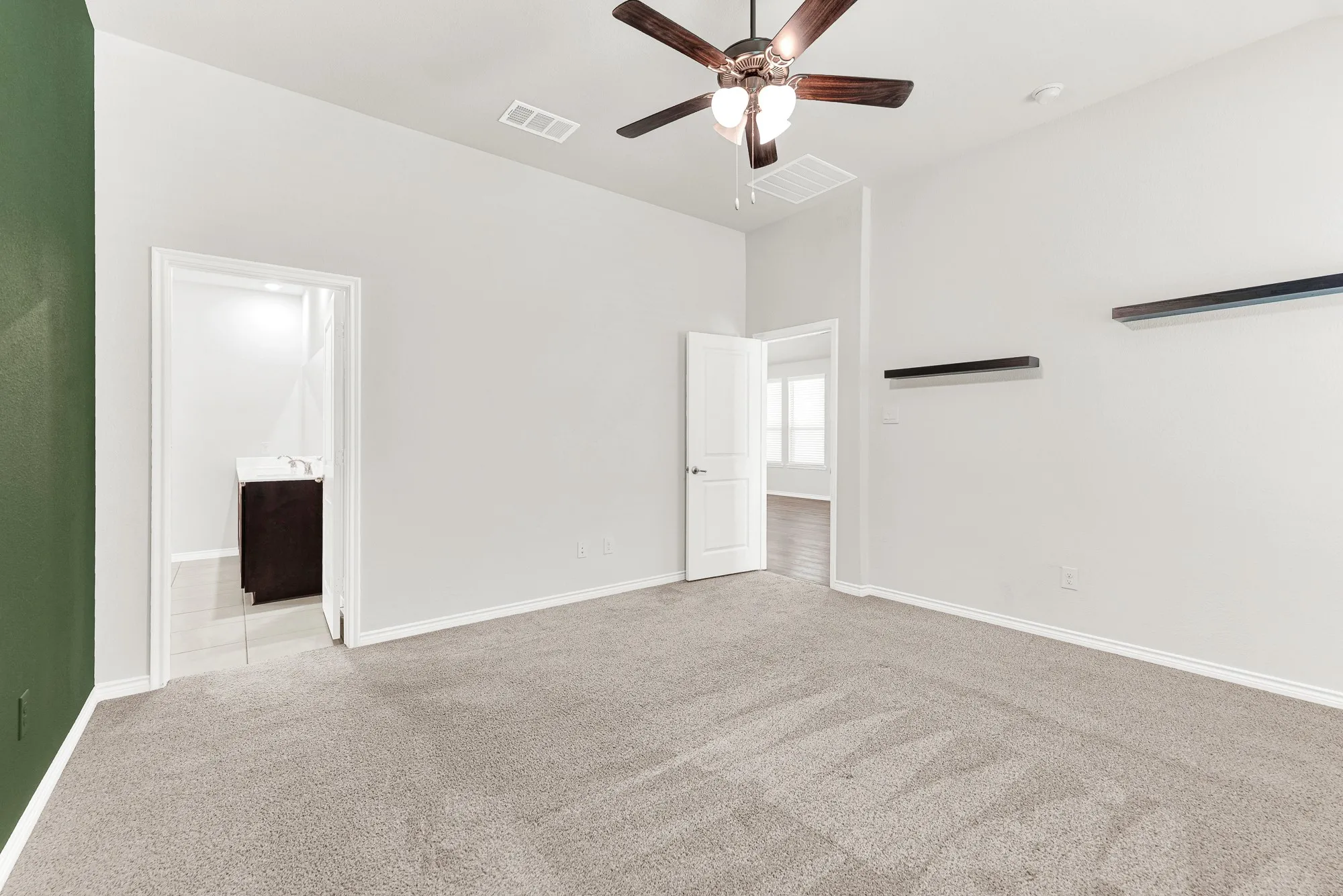 This viewpoint connects the peaceful bedroom area, including its wall shelves and ceiling fan, directly to the large window view and the entrance of the spa-inspired ensuite bathroom. Experience effortless luxury as you move freely between your private relaxation space and the well-appointed bathroom.