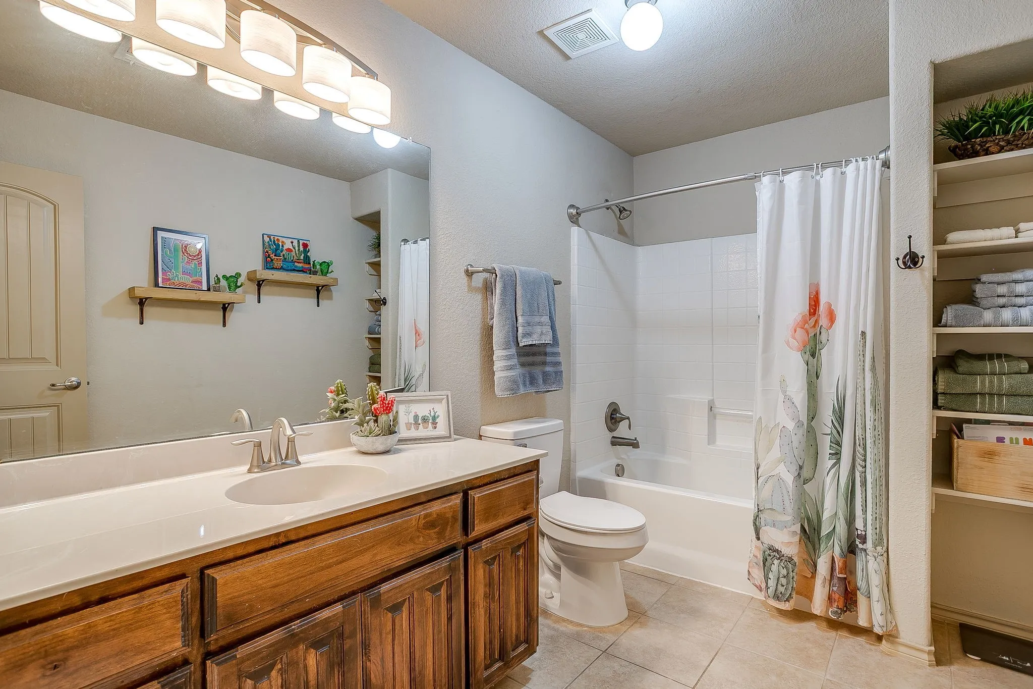 Hall bathroom with oversized vanity, single sink and shower tub combo.  Built in linen storage.