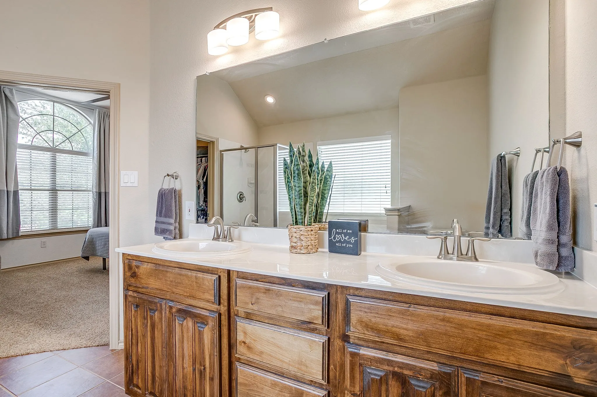 Dual sinks, rich wood cabinetry, large vanity mirror and dual lighting.