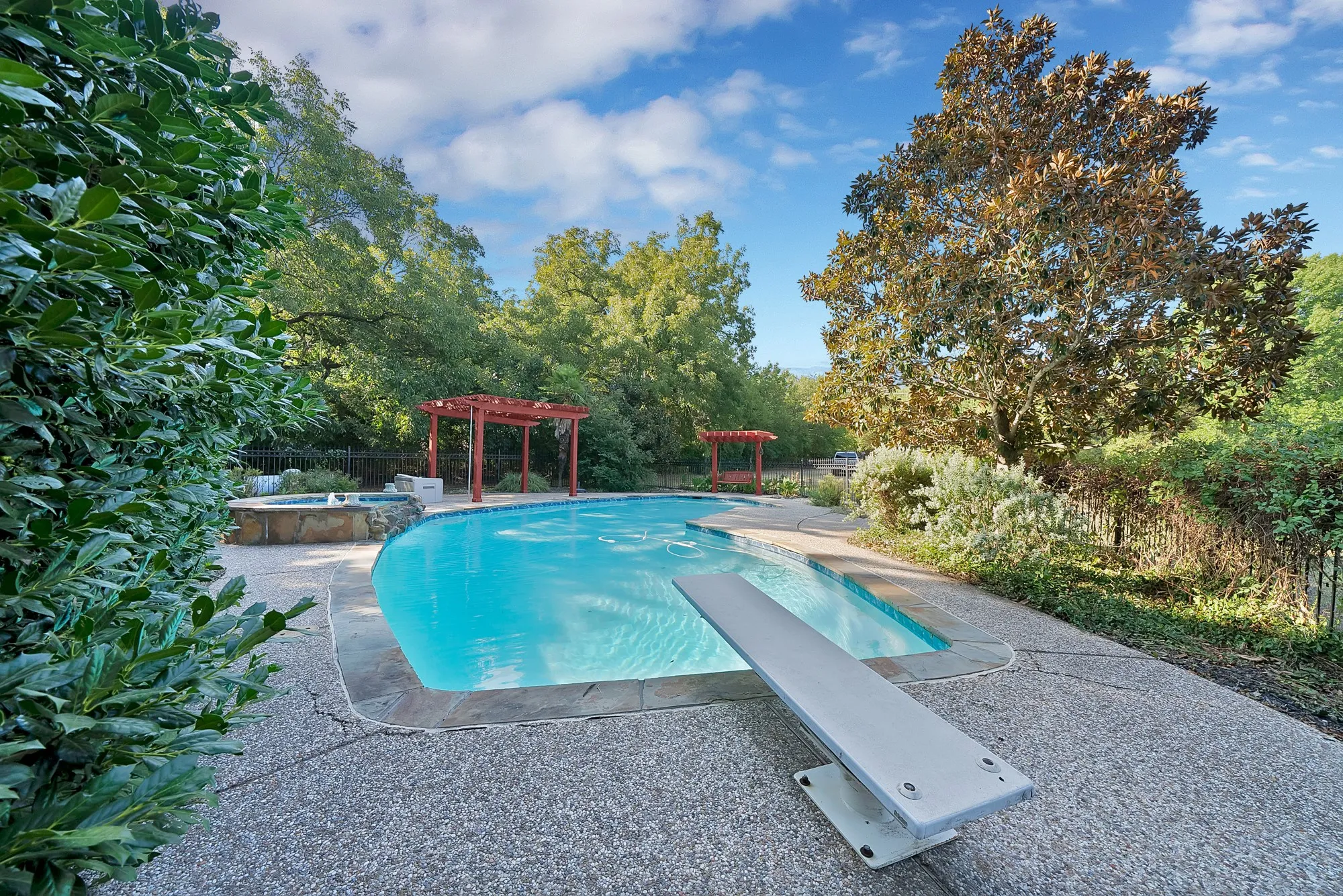 48 foot in-ground pool with a diving board, surrounded by concrete decking