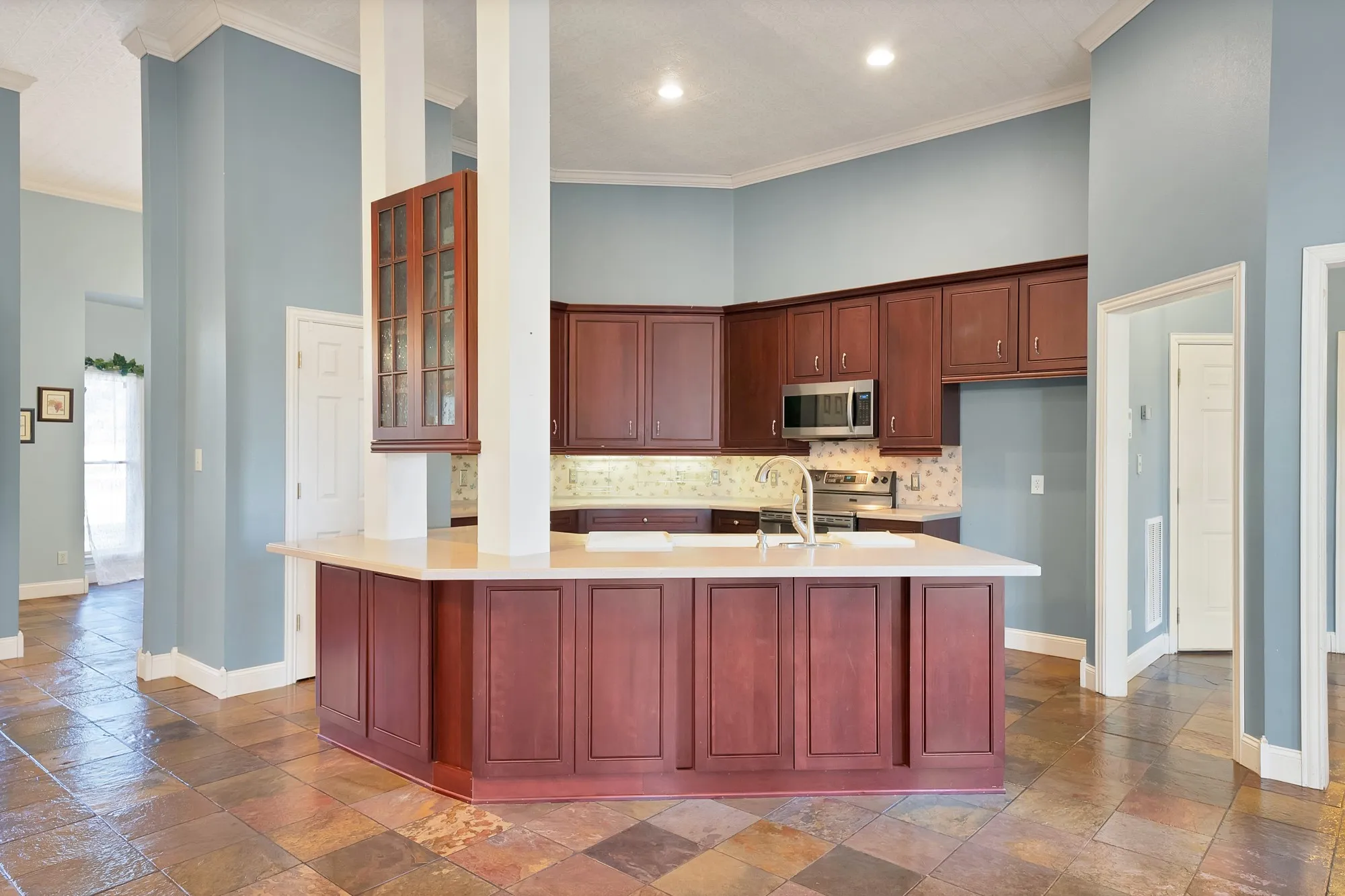 Kitchen featuring recessed lighting, a built-in microwave, wood-finish cabinetry, a large kitchen island with a light-colored countertop, and a tile backsplash
