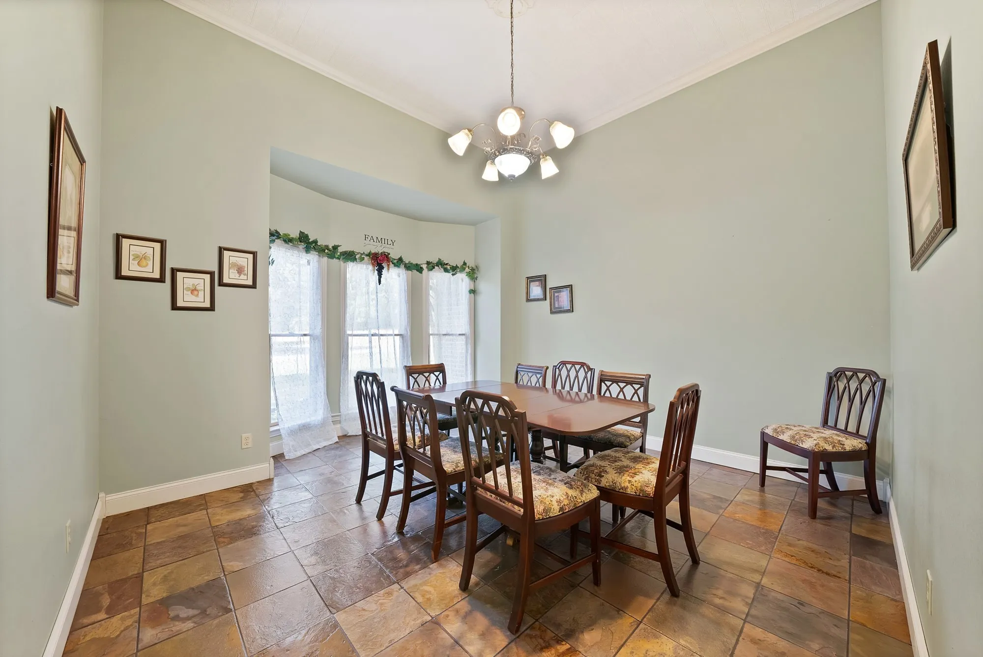 Vaulted ceiling, bay windows, chandelier lighting, slate floor tiles, and crown molding