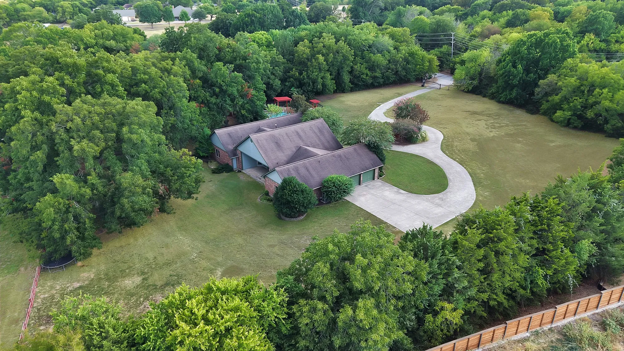 Expansive lot featuring mature trees, a long curved driveway, and a multi-gabled roofline