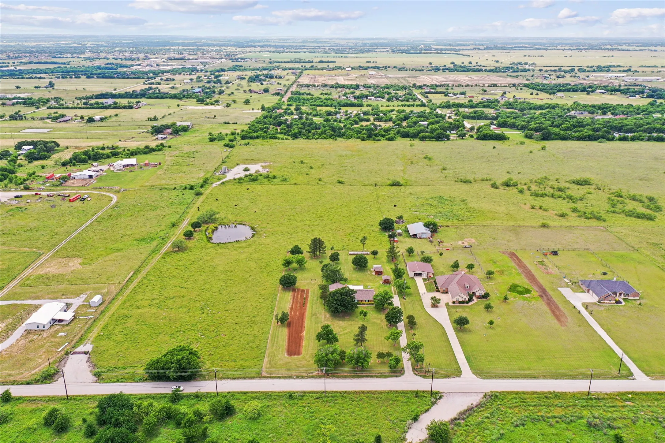 Expansive rural property featuring a private pond, multiple structures, and extensive green space