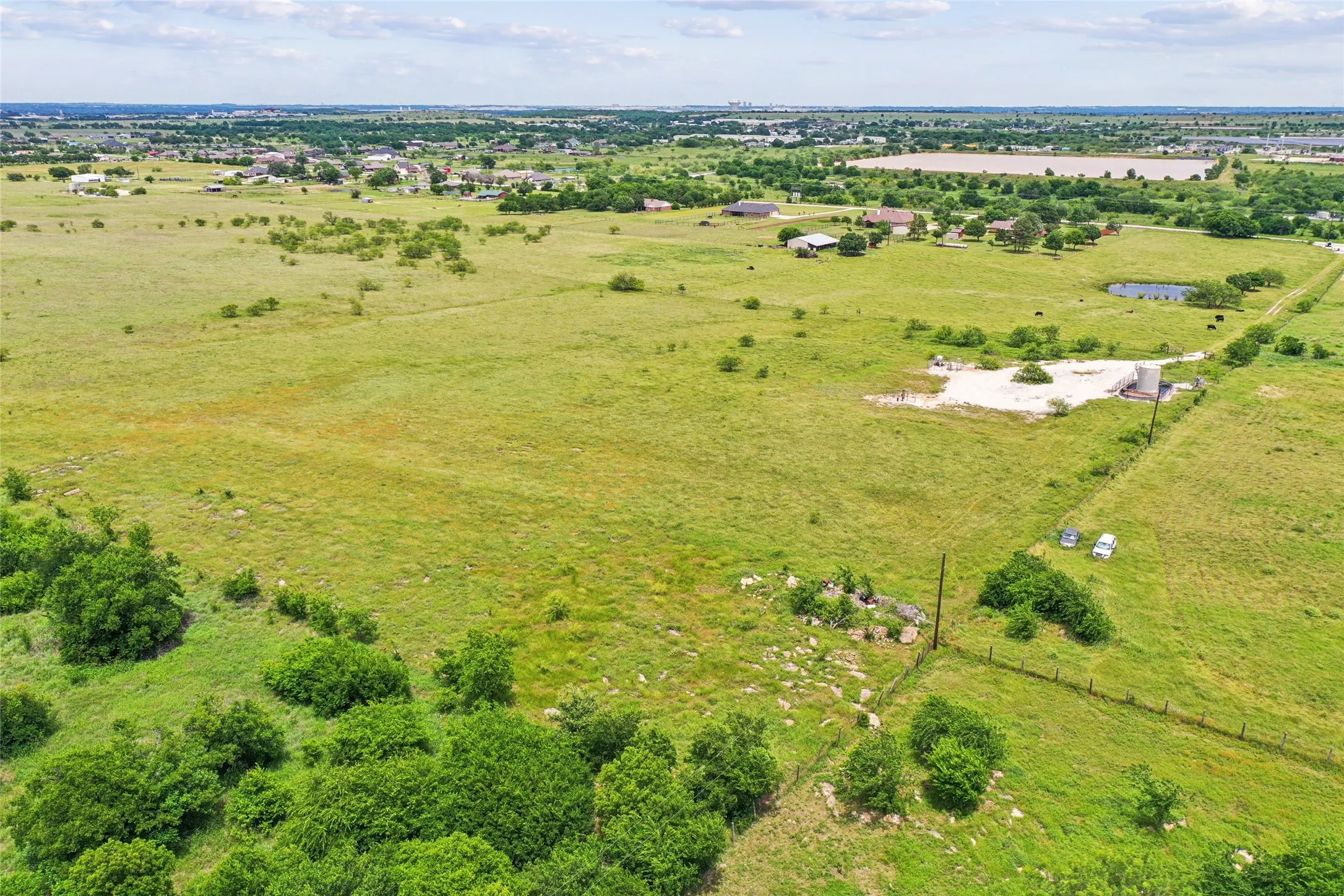 Expansive green acreage featuring scattered trees and established fencing