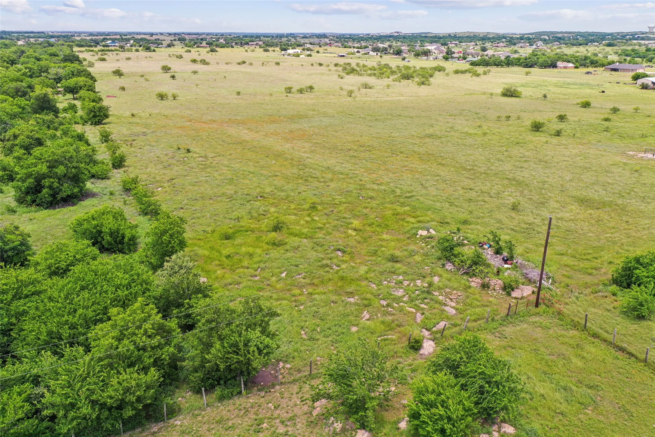 Expansive undeveloped land featuring natural foliage and a visible perimeter fence