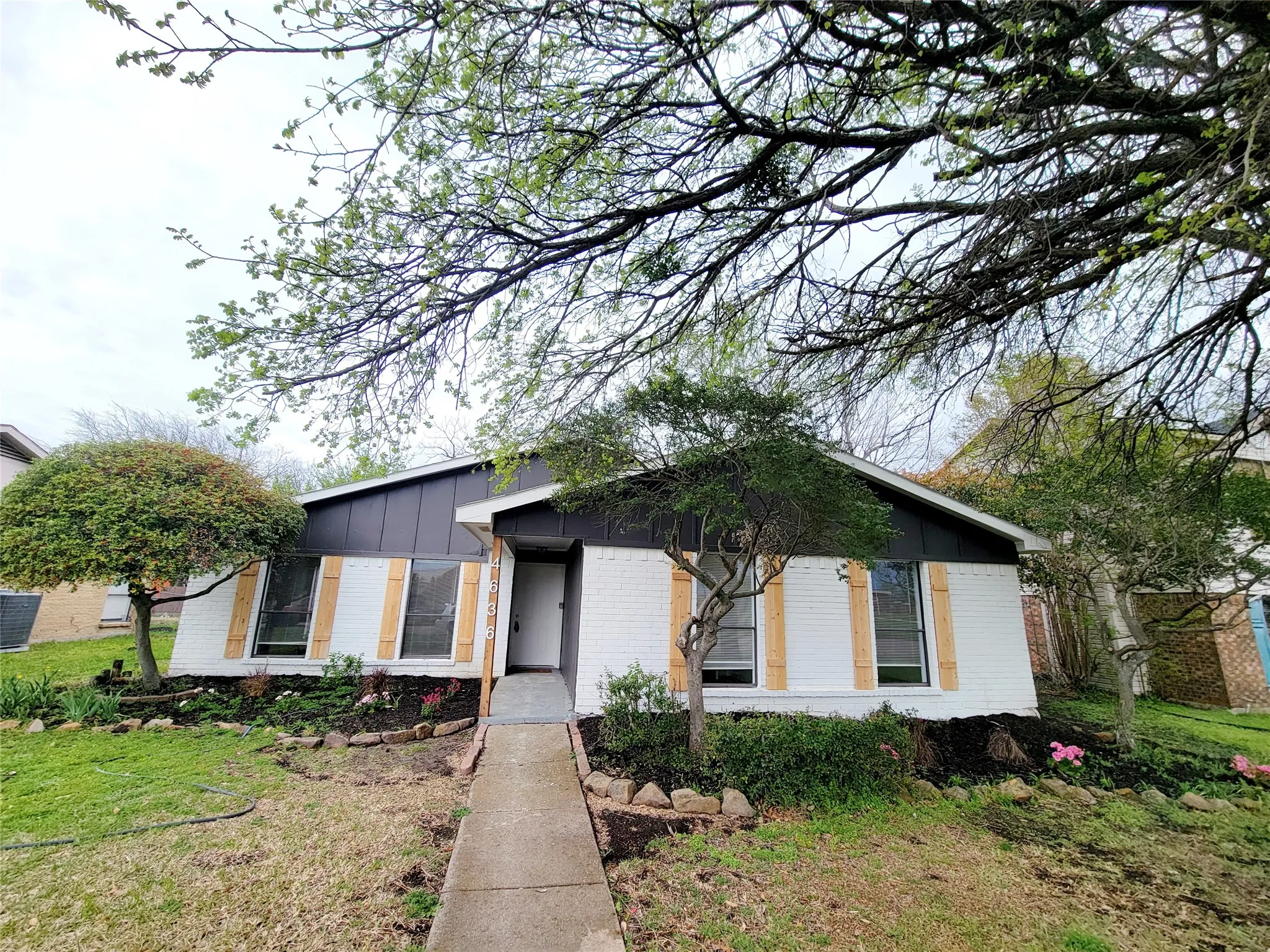 View of front of house featuring board and batten siding, brick siding, and a front yard