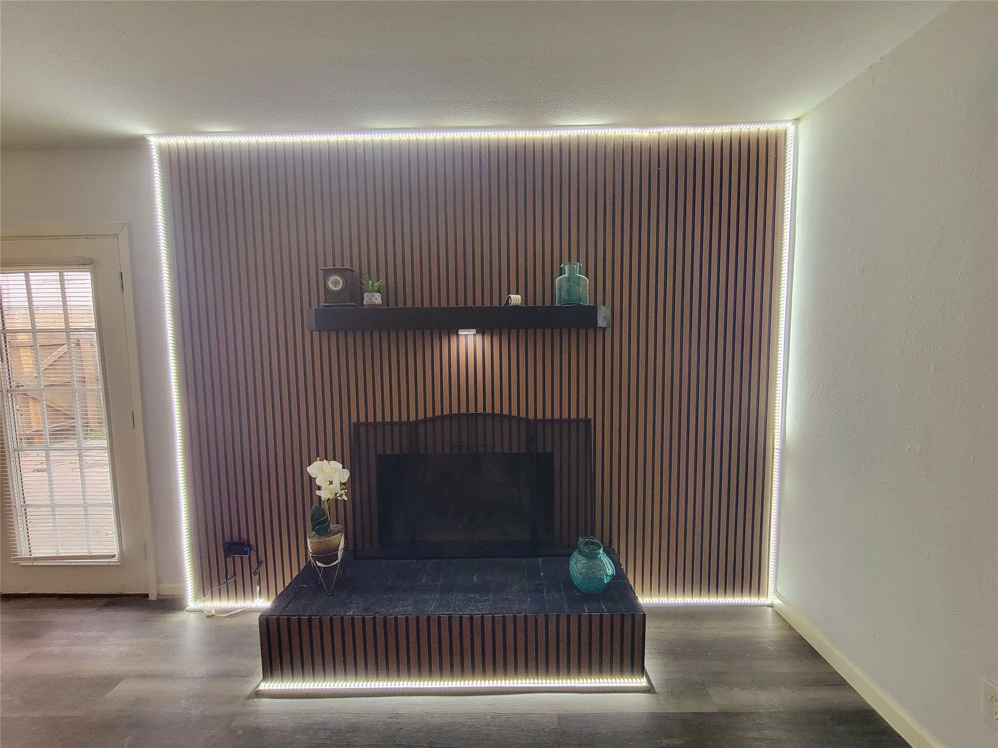 Room details with a fireplace with raised hearth, baseboards, and wood finished floors