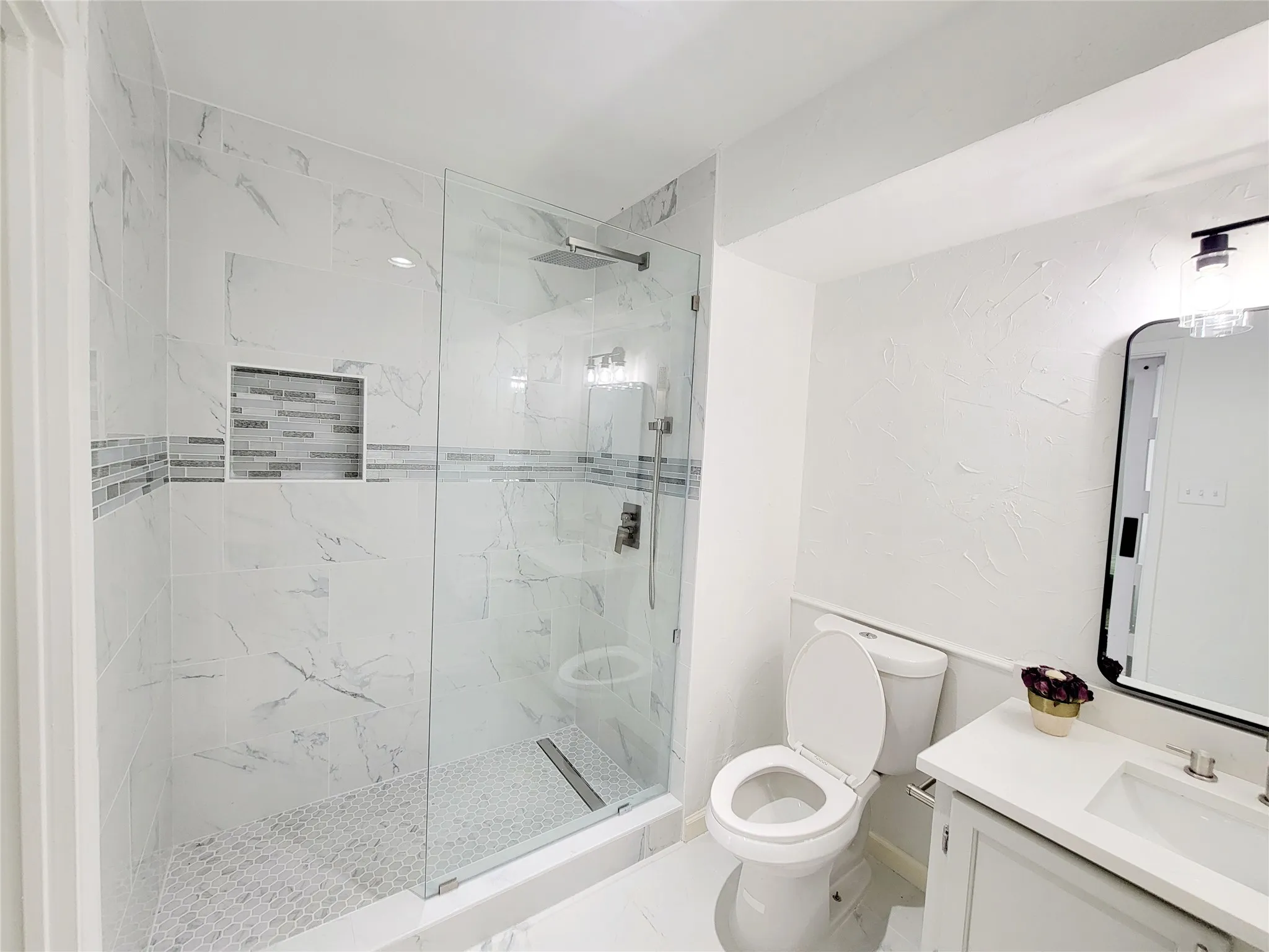 Full bath with toilet, vanity, and a marble finish shower