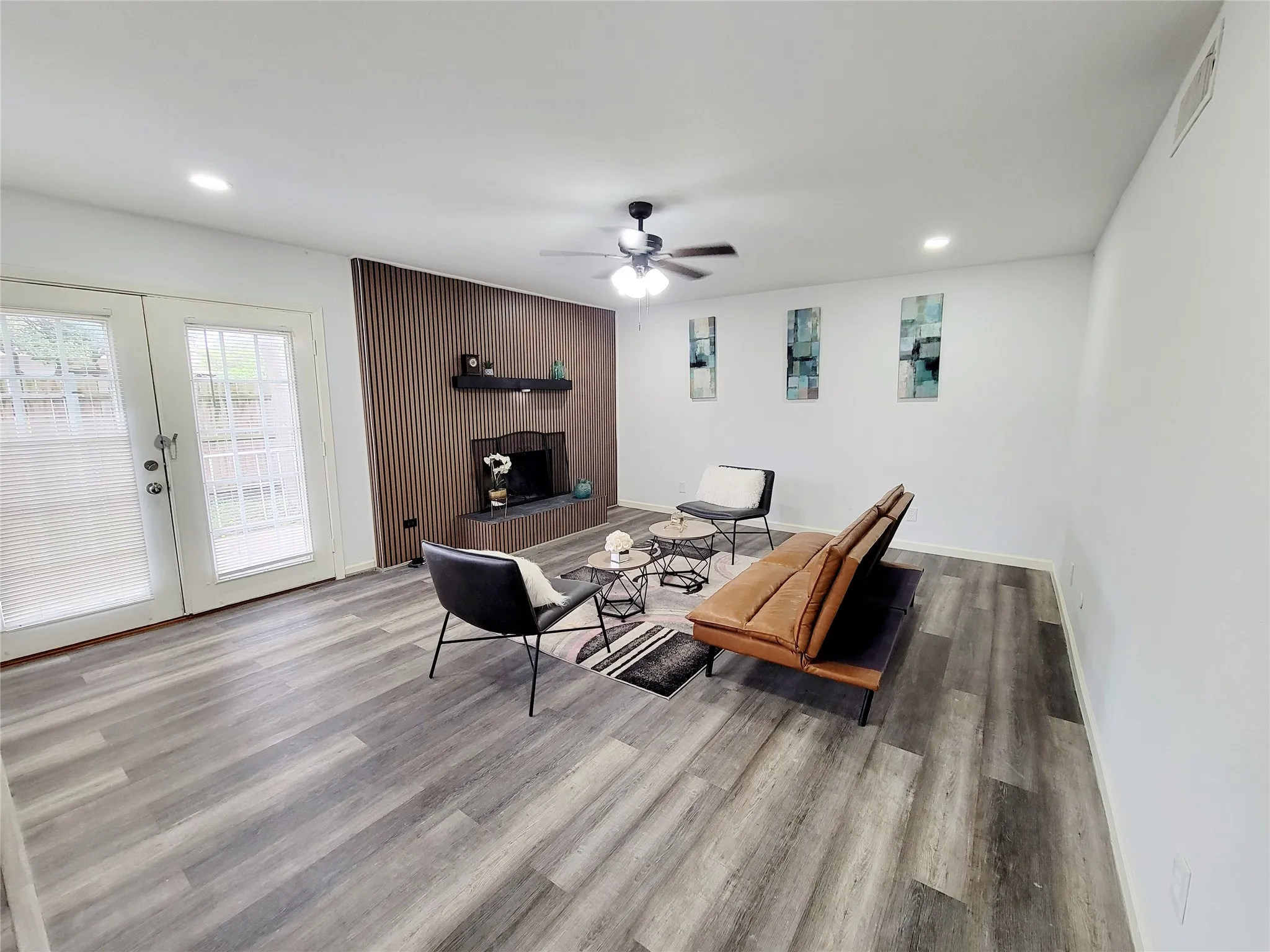 Living area featuring french doors, visible vents, a ceiling fan, a fireplace, and wood finished floors