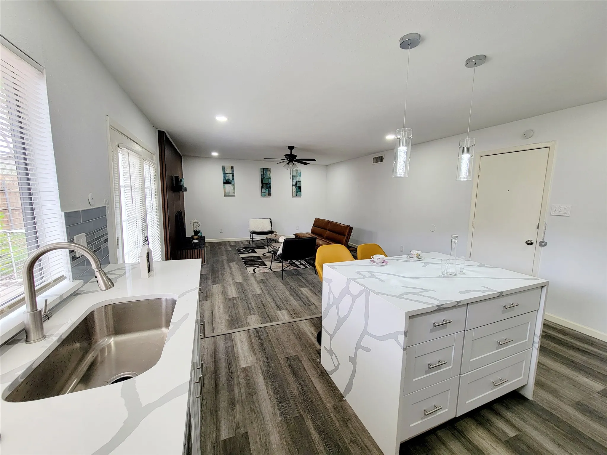 Kitchen featuring ceiling fan, a sink, decorative light fixtures, dark wood-style floors, and a center island