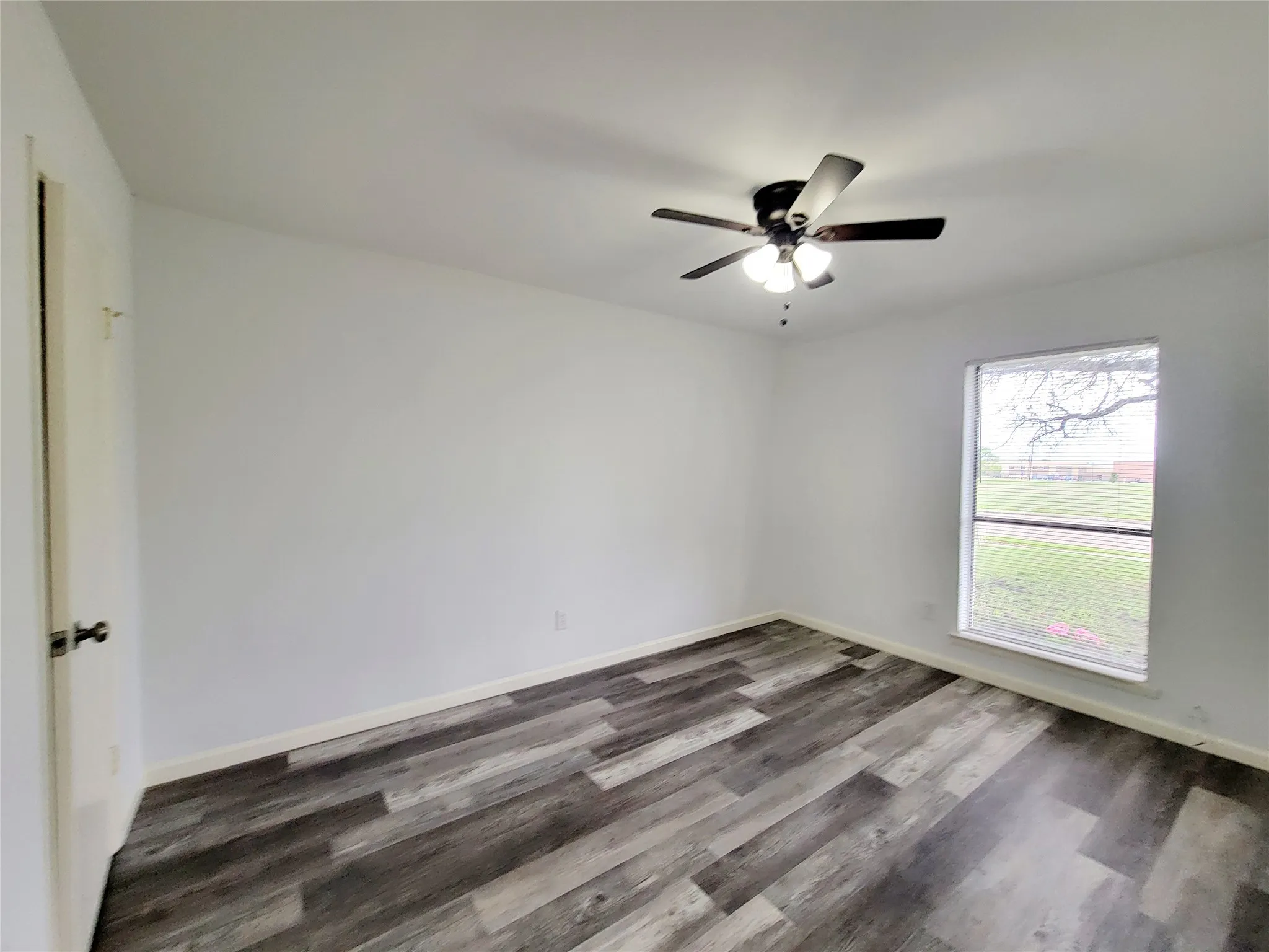 Spare room featuring baseboards, dark wood-style floors, and ceiling fan