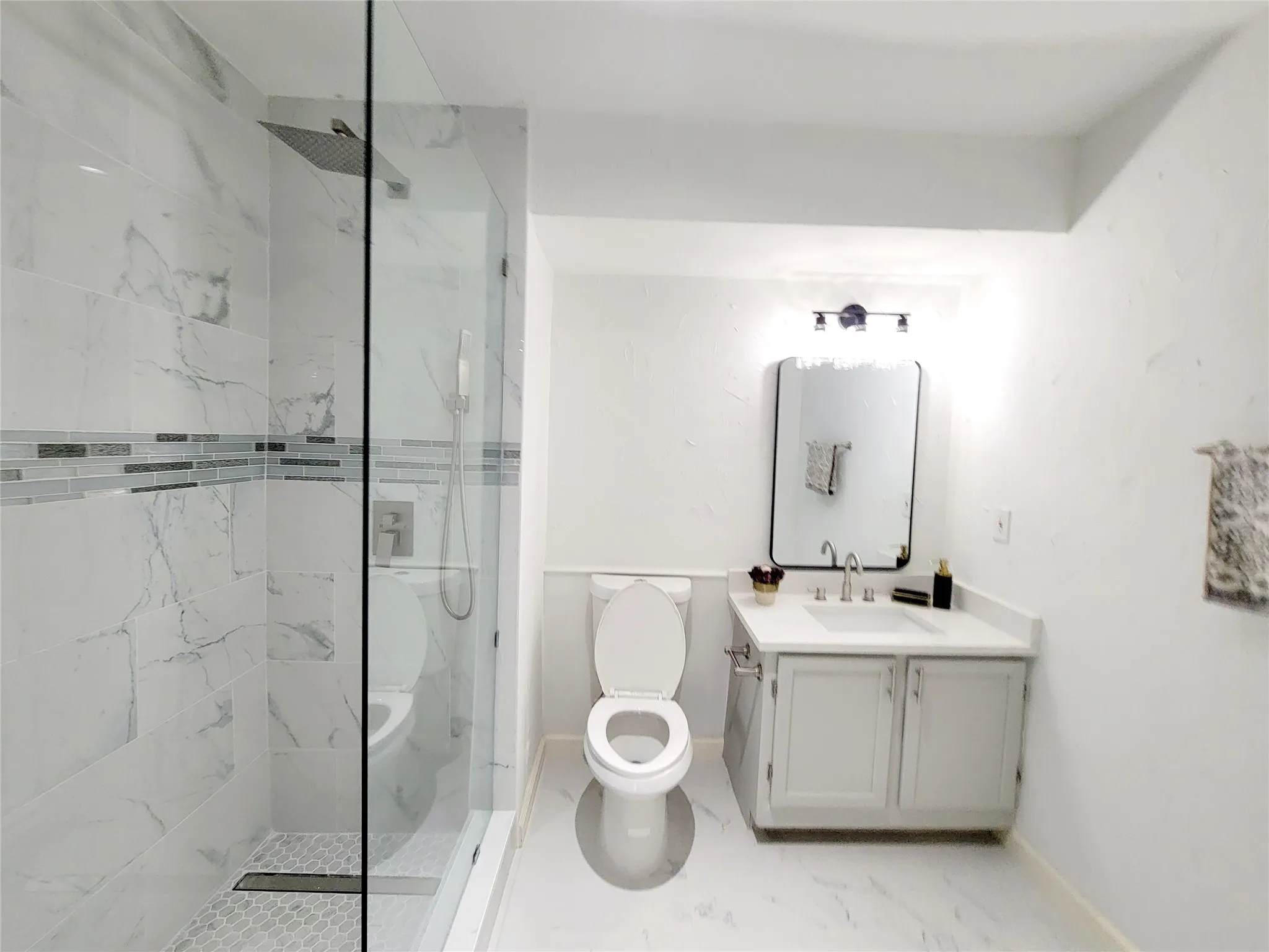 Full bathroom featuring baseboards, marble finish floor, a marble finish shower, toilet, and vanity