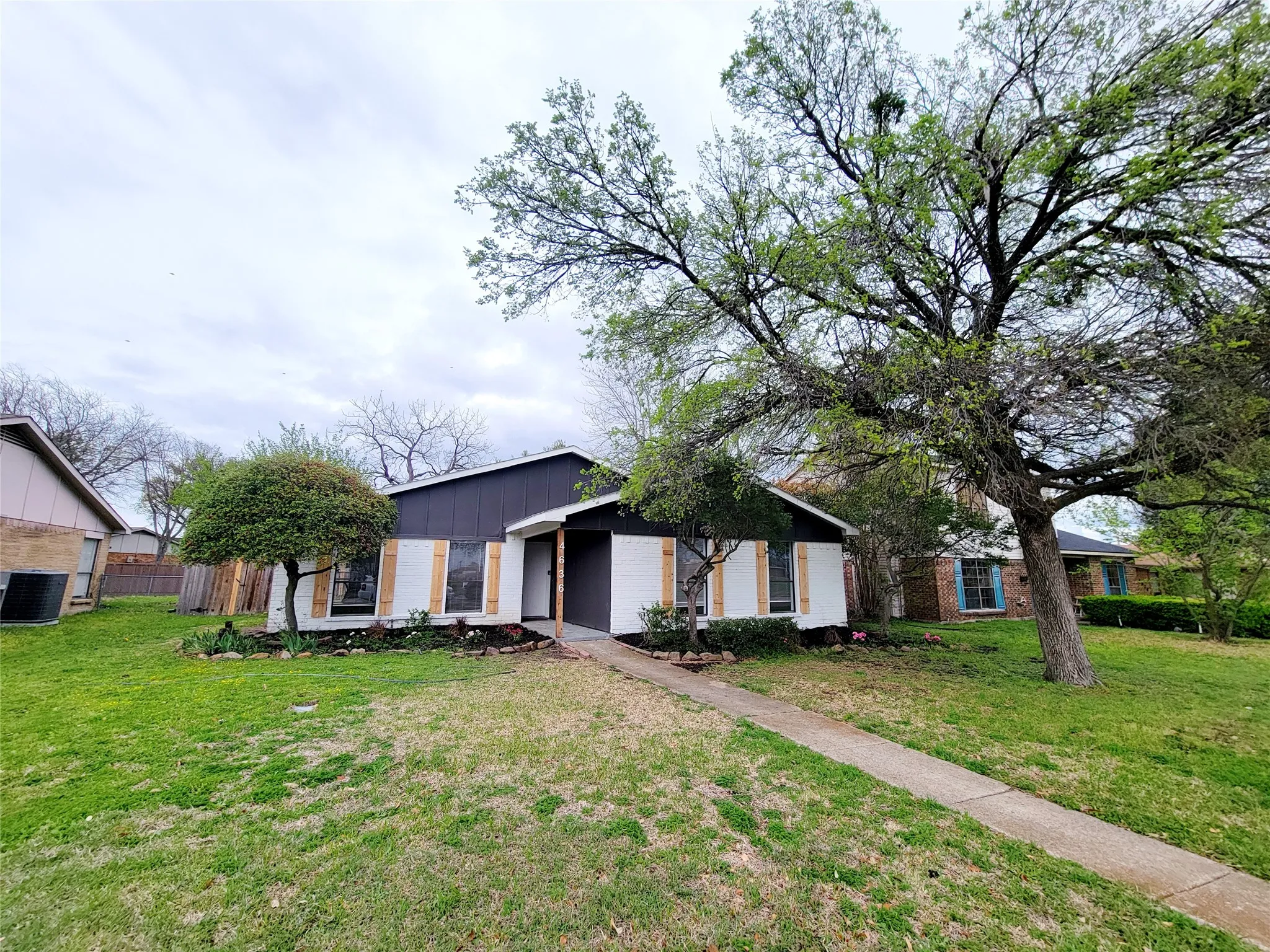 Mid-century inspired home with a front lawn, cooling unit, and fence