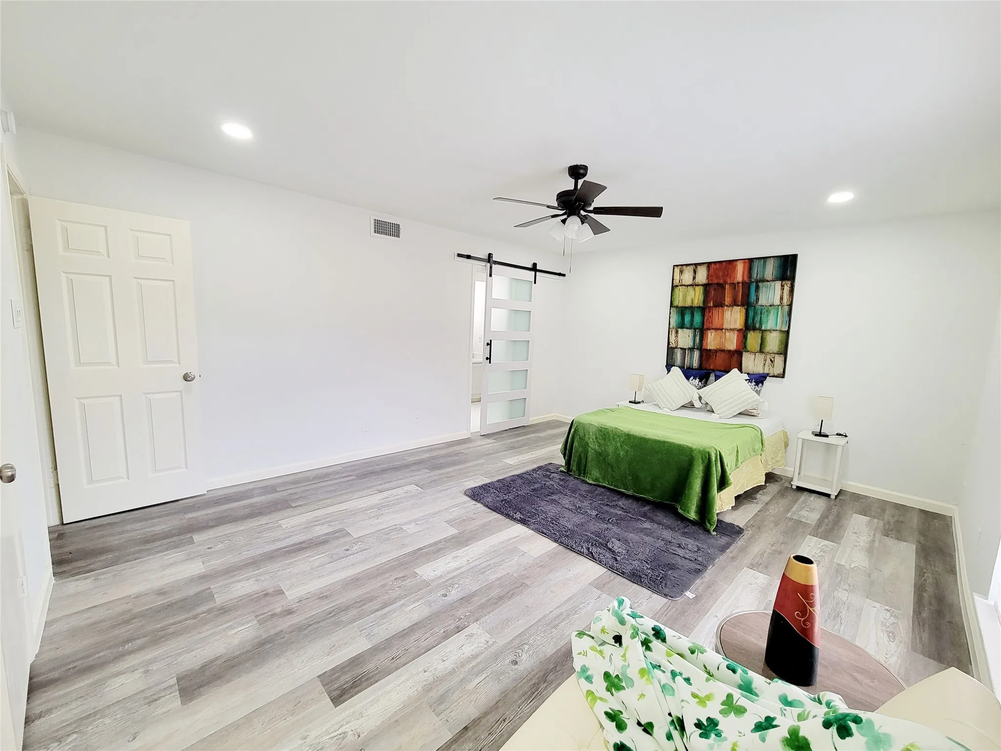 Bedroom featuring wood finished floors, recessed lighting, a barn door, and visible vents