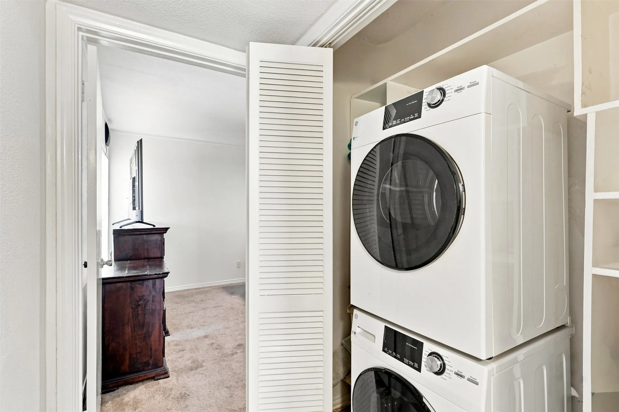 Convenient in-home laundry area with stacked washer and dryer and additional storage.