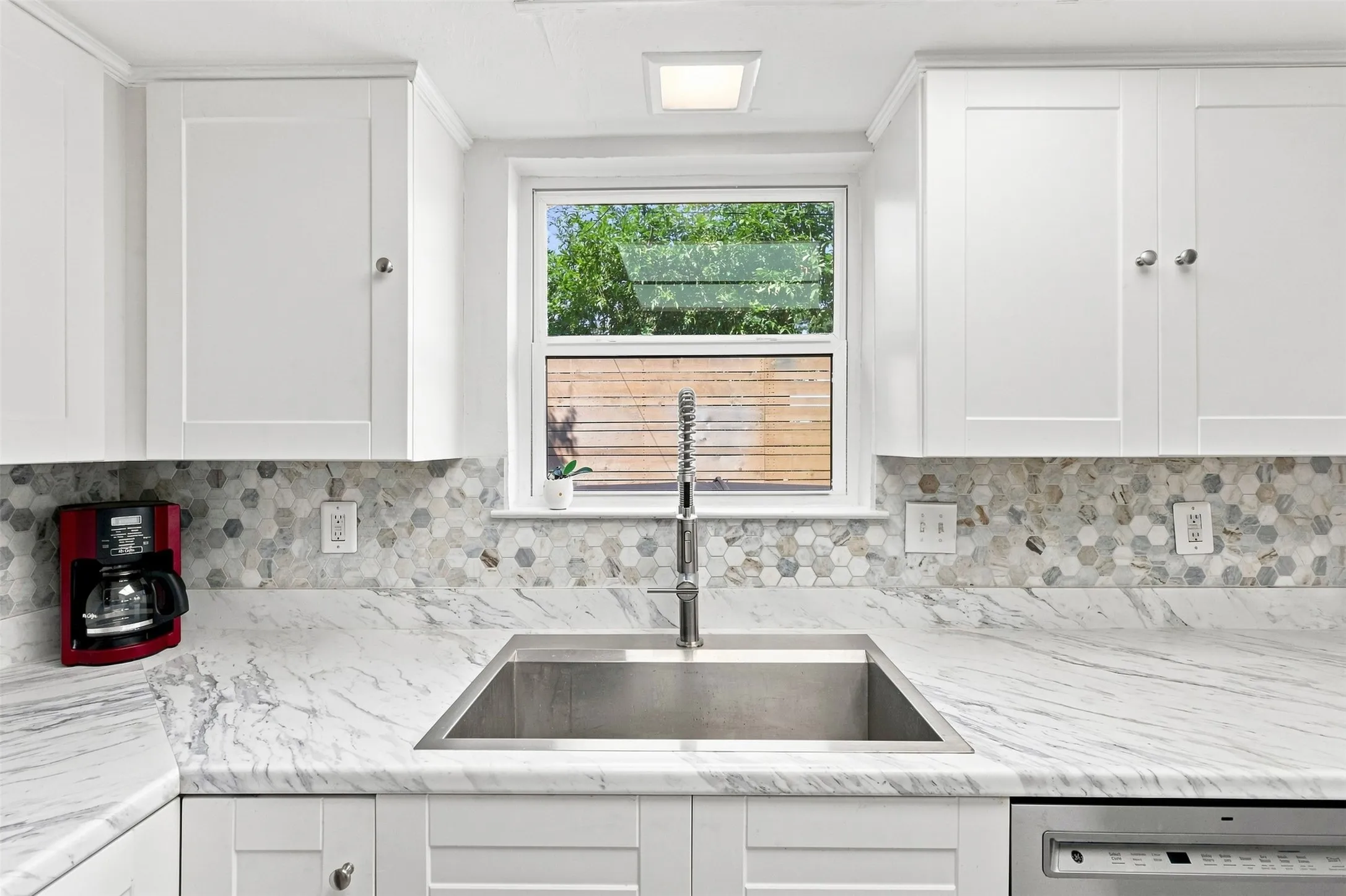 Generous counter space, updated cabinetry, modern backsplash, and an oversized undermount sink.