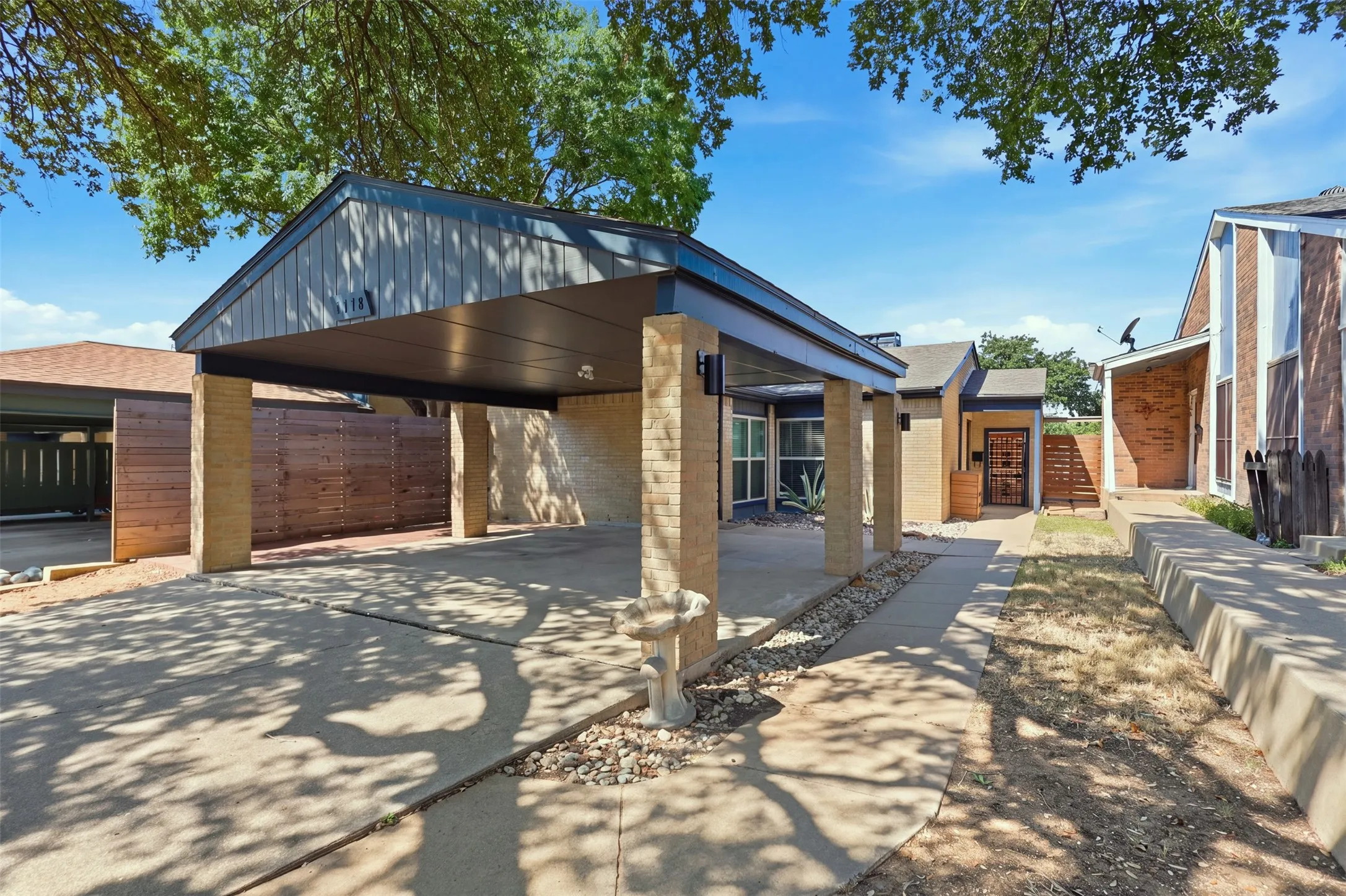 Single-story townhome with two-car covered carport and mature shade trees.