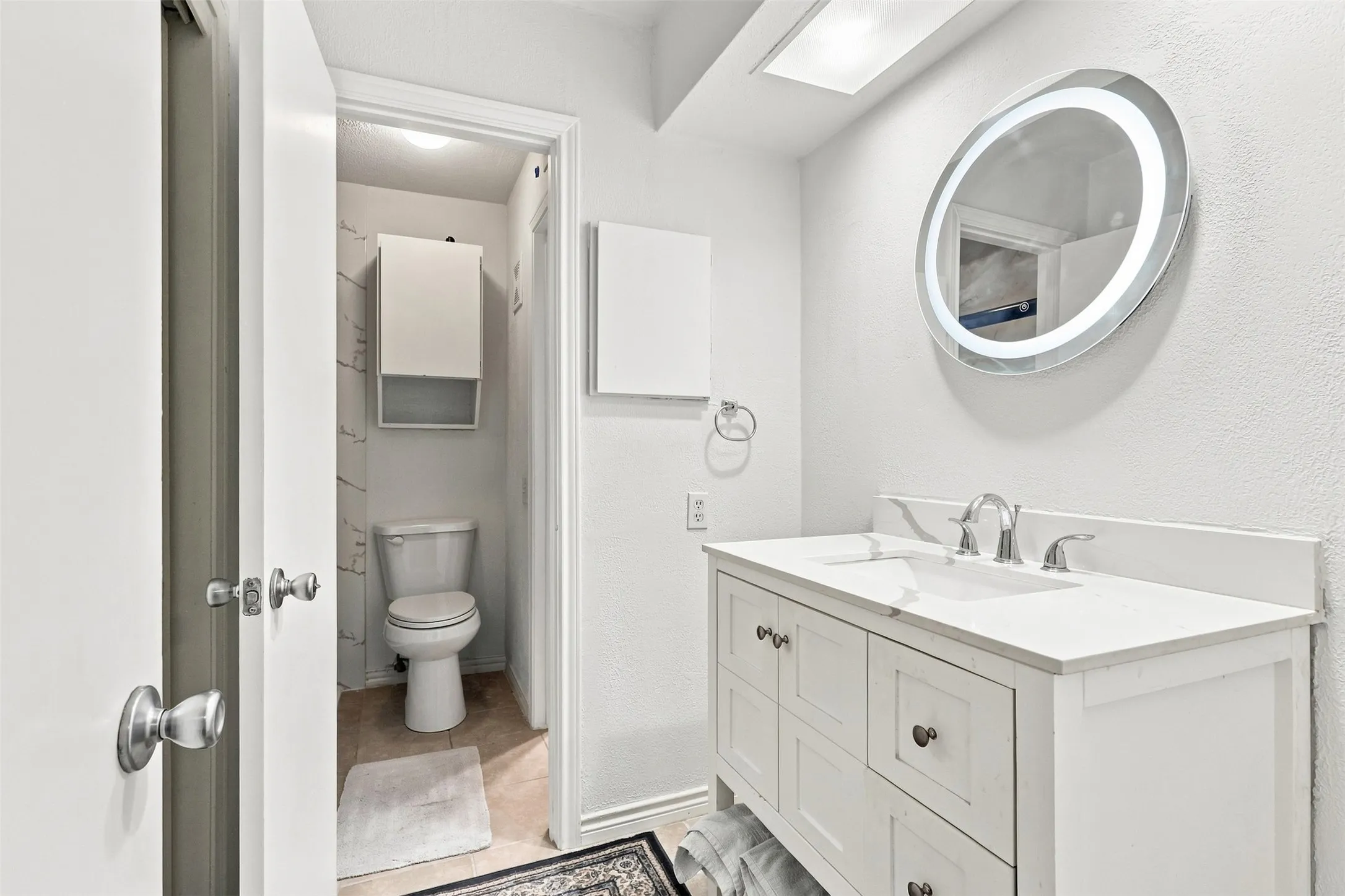 Updated powder bath with contemporary vanity and illuminated mirror.