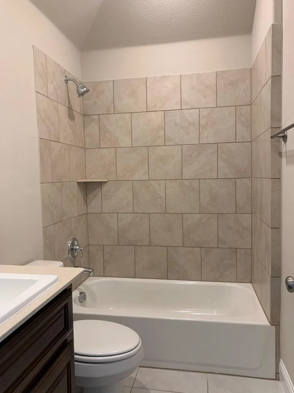 Bathtub with tiled surround, integrated showerhead, and wall-mounted towel bar