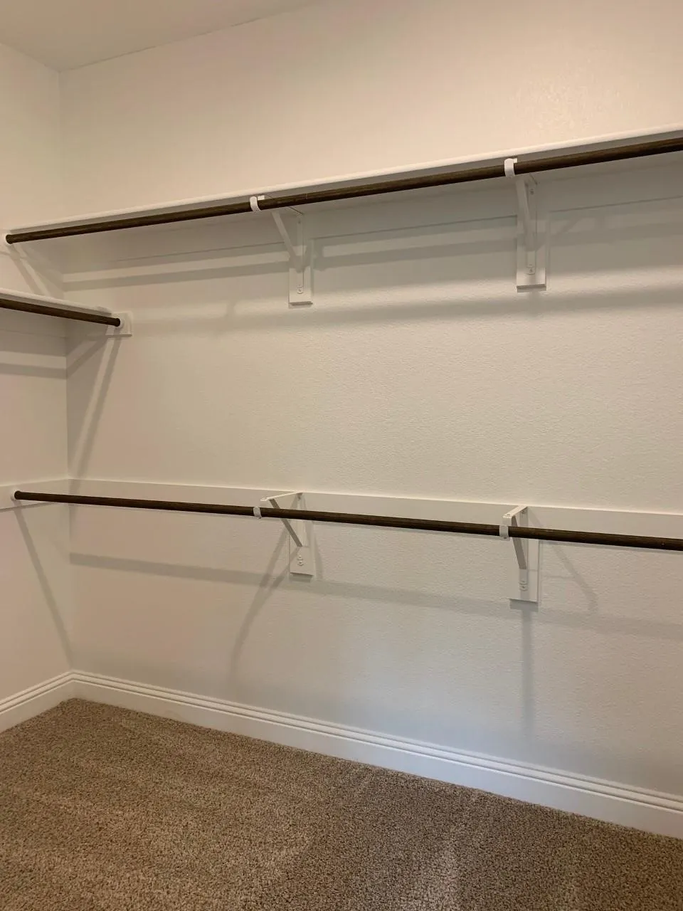 Built-in shelving with hanging rods and carpet flooring