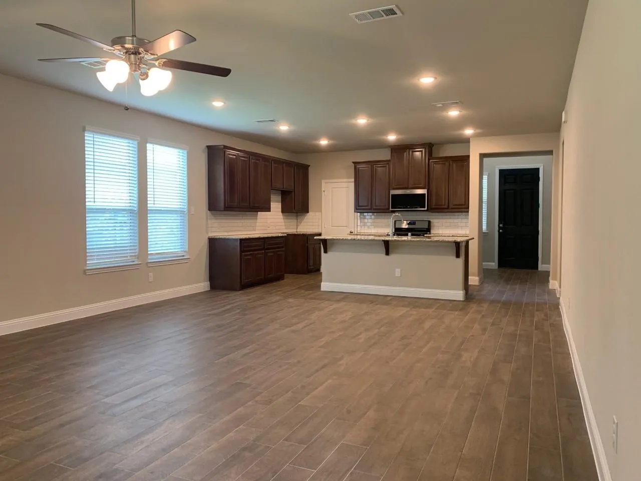 Open-concept living space with wood-finish tile flooring, recessed lighting, and a ceiling fan