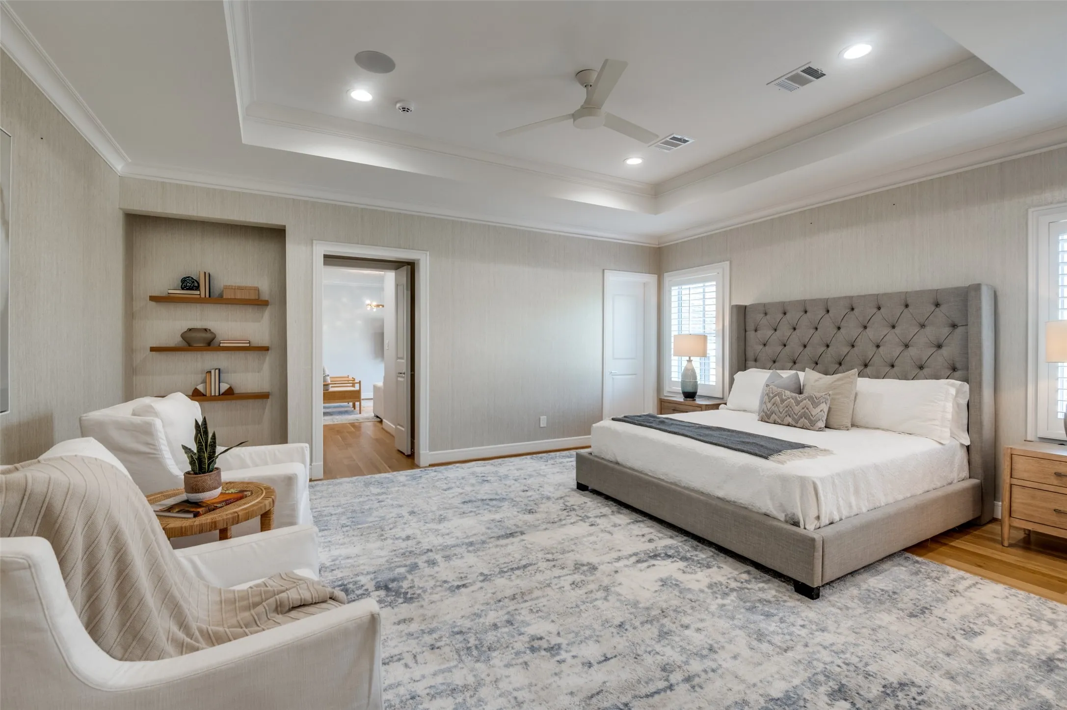Tray ceiling with recessed lighting and a ceiling fan, hardwood flooring, built-in shelving, and plantation shutters