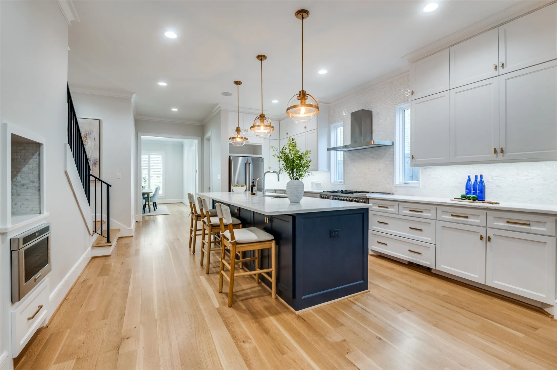 Light wood-finish flooring, a kitchen island with a light-colored countertop, recessed lighting, white cabinetry, and stainless steel appliances