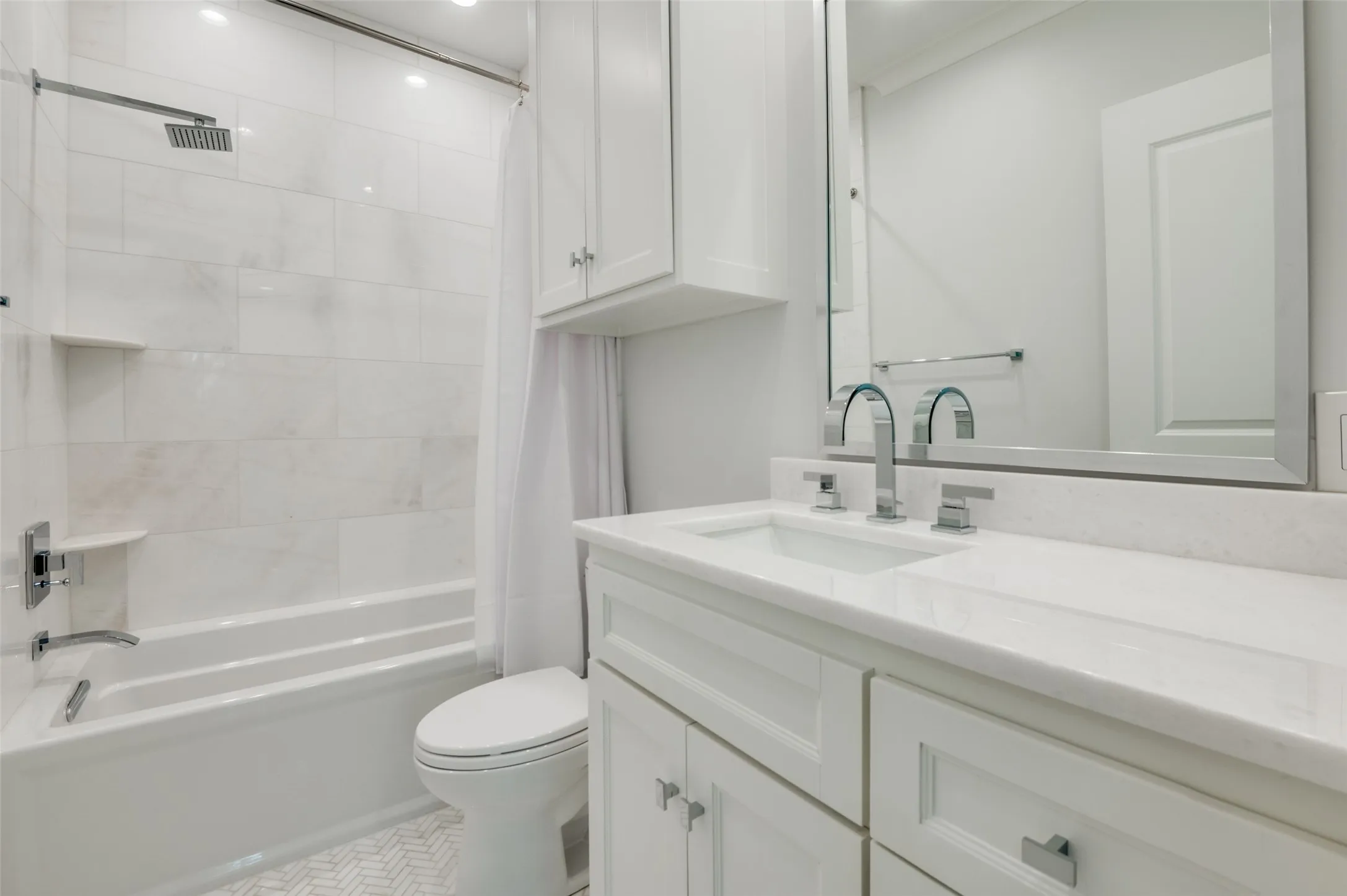 Bathroom featuring a white vanity with integrated sink, chrome fixtures, built-in medicine cabinet, and white subway tile bath surround