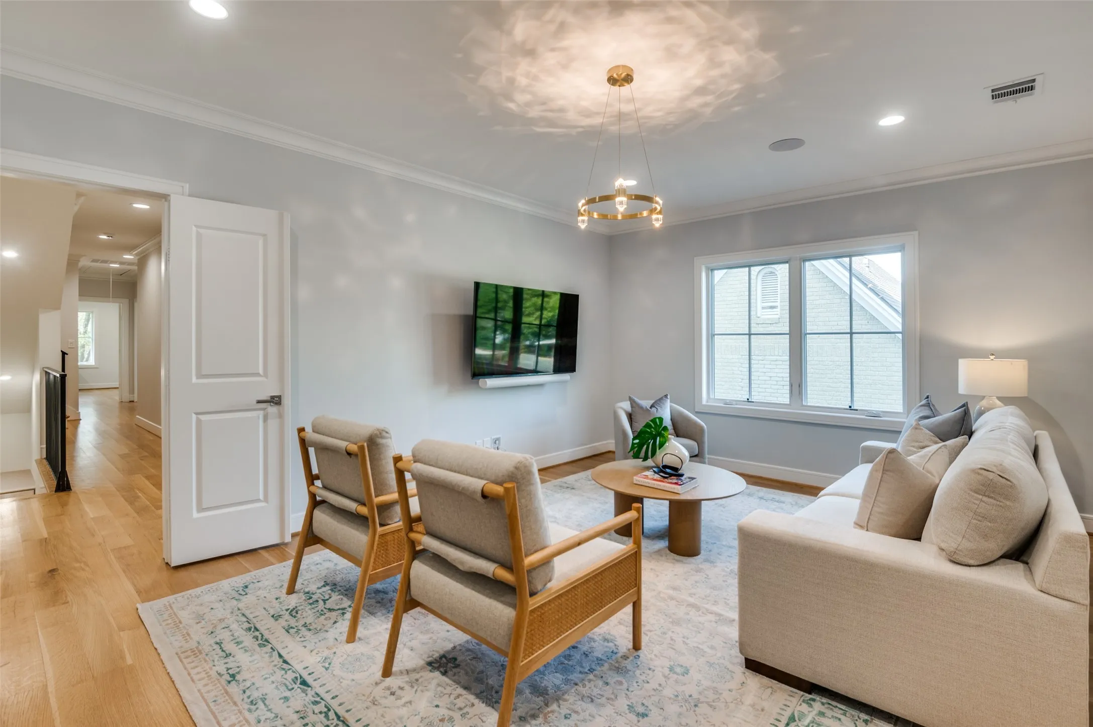 Hardwood flooring, recessed lighting, crown molding, modern chandelier, and a bright window with grilles