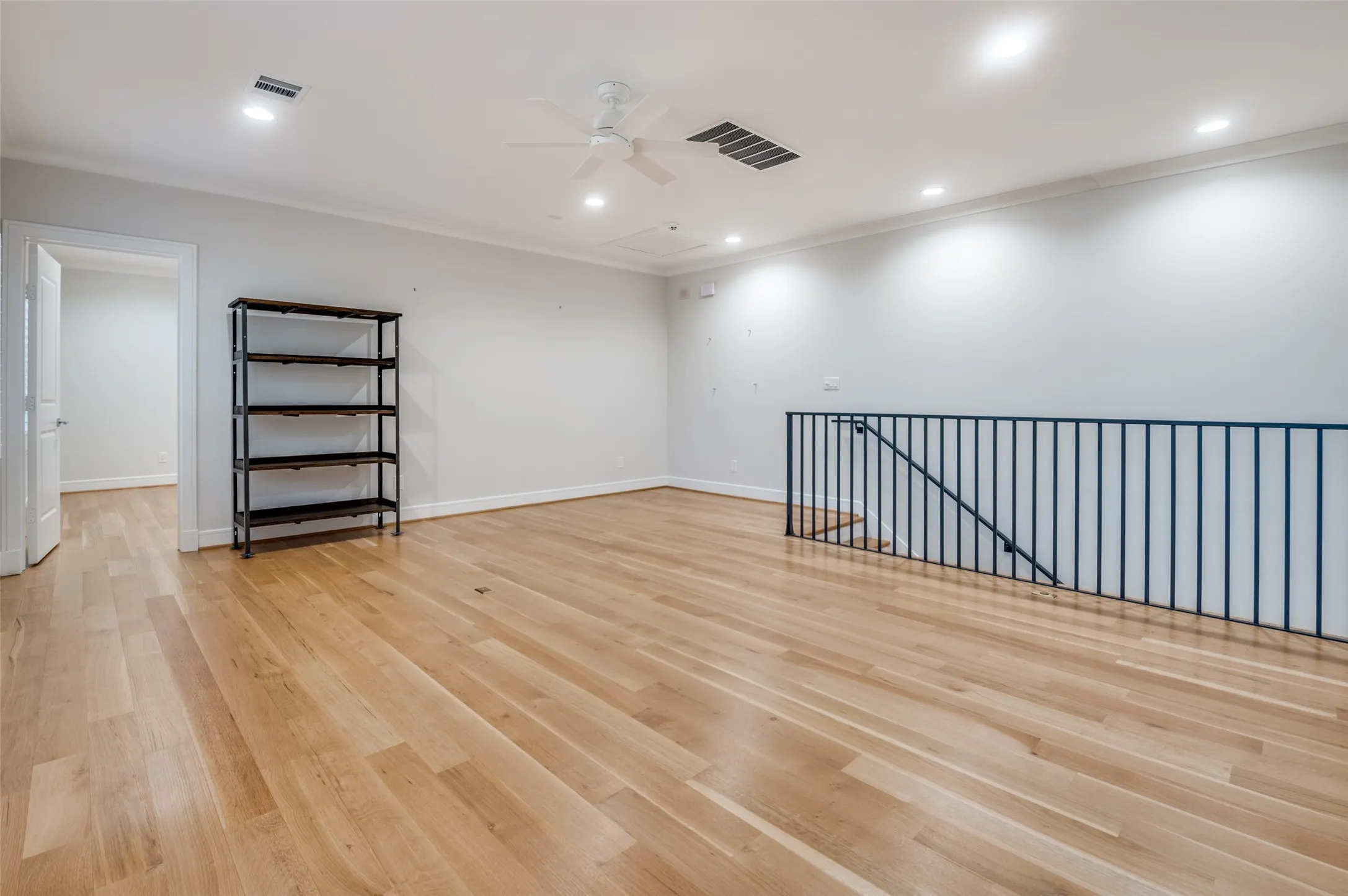 Hardwood flooring, recessed lighting, ceiling fan, crown molding, and wrought iron railing