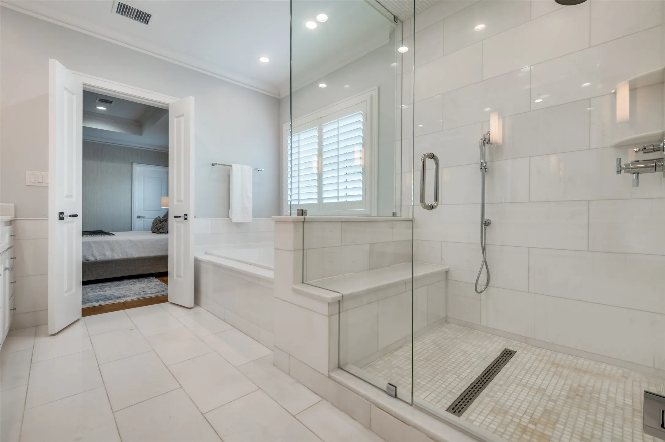 Spacious bathroom featuring a glass-enclosed shower with bench, built-in tub, and tile flooring