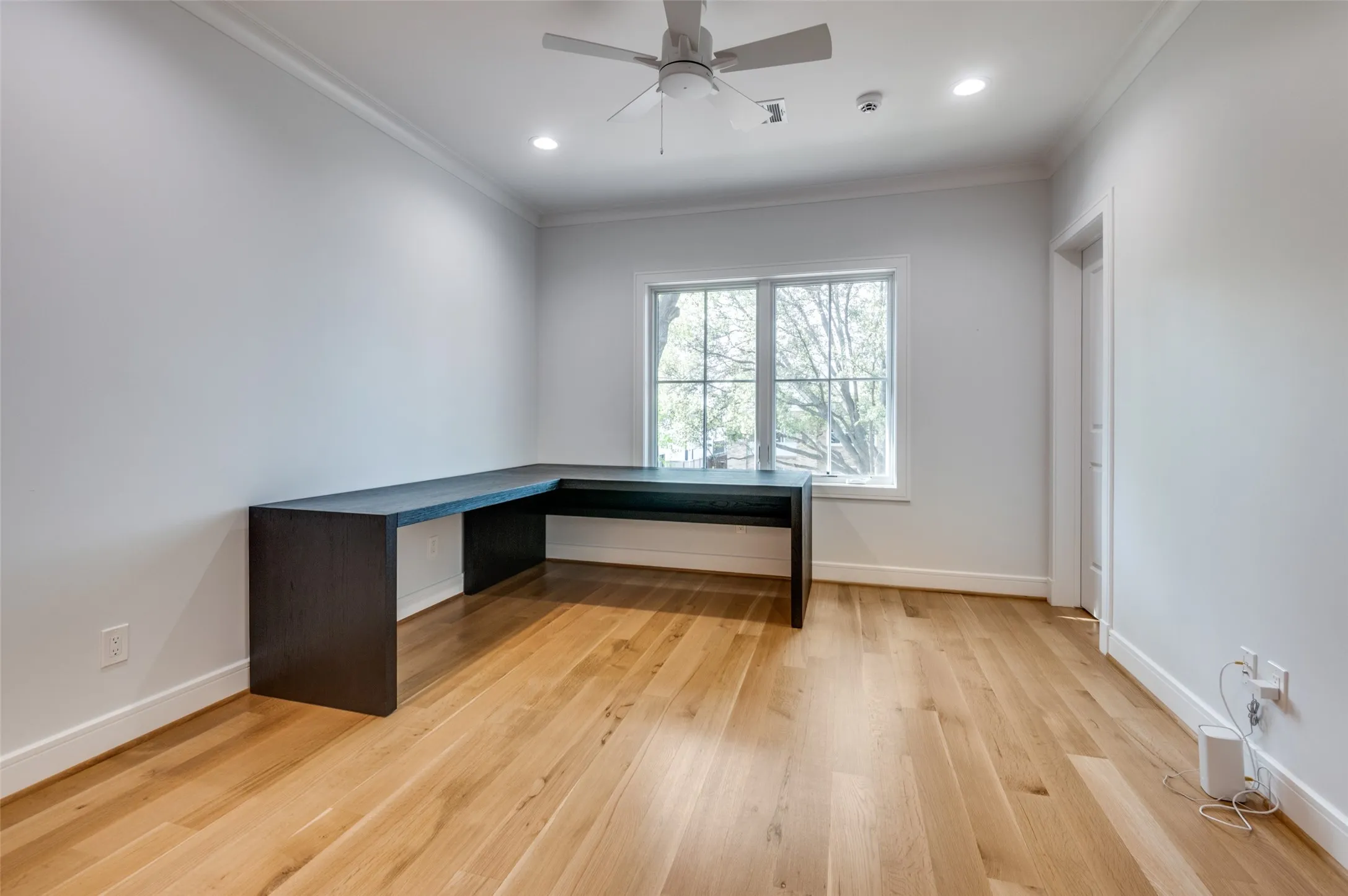 Recessed lighting, wood-finish flooring, crown molding, built-in desk, and a ceiling fan