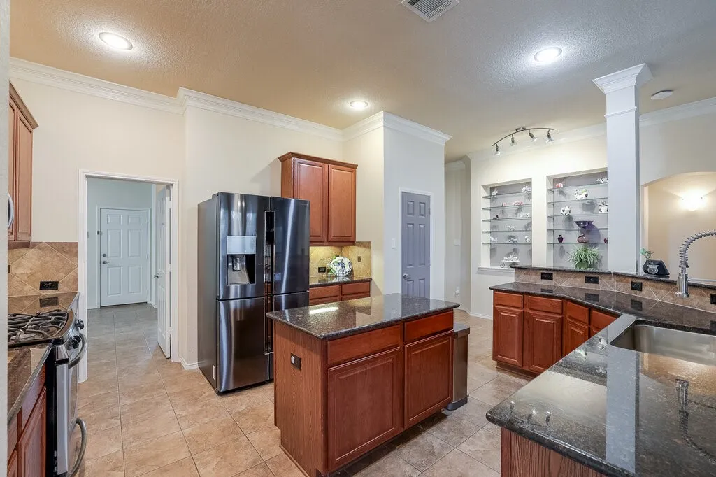 Turn the corner to view expansive island kitchen wrapped with breakfast bar & open to den.