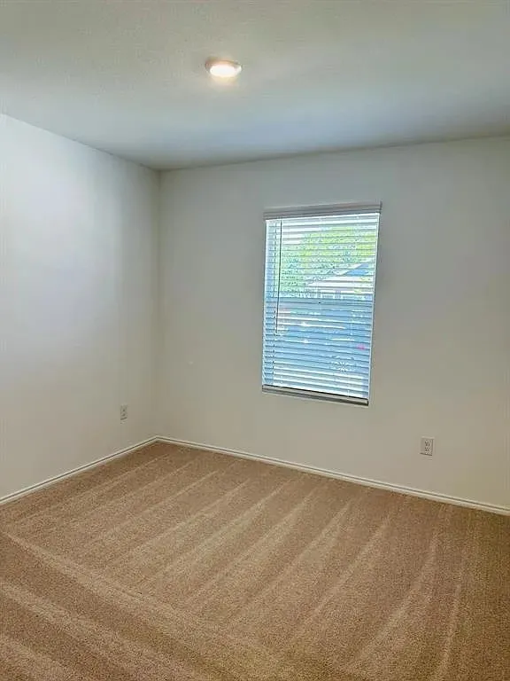 Recessed ceiling light, neutral wall paint, window with blinds, and light-colored carpeting