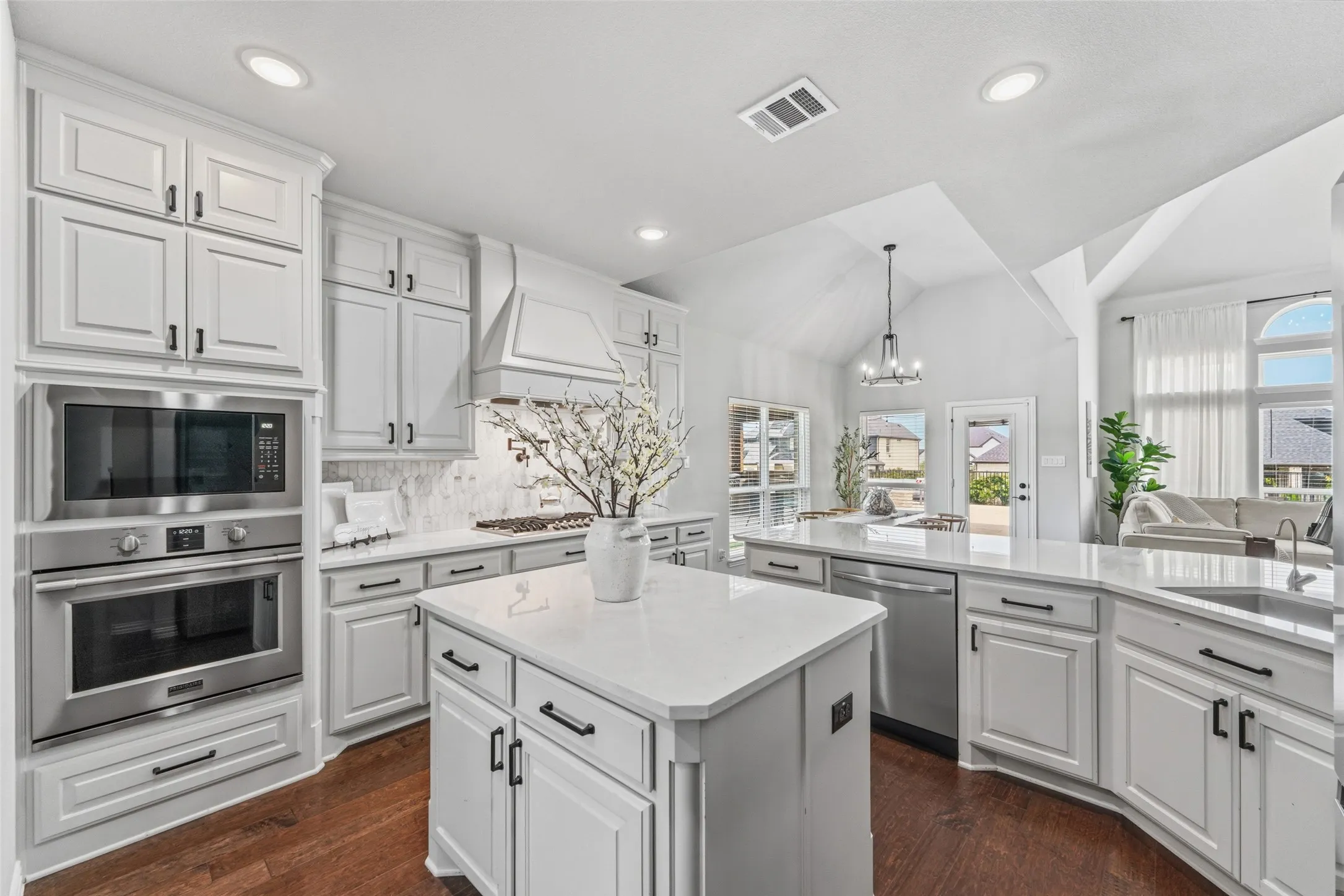 Gourmet kitchen featuring white cabinetry with brushed nickel hardware, quartz countertops, and a large center island with storage