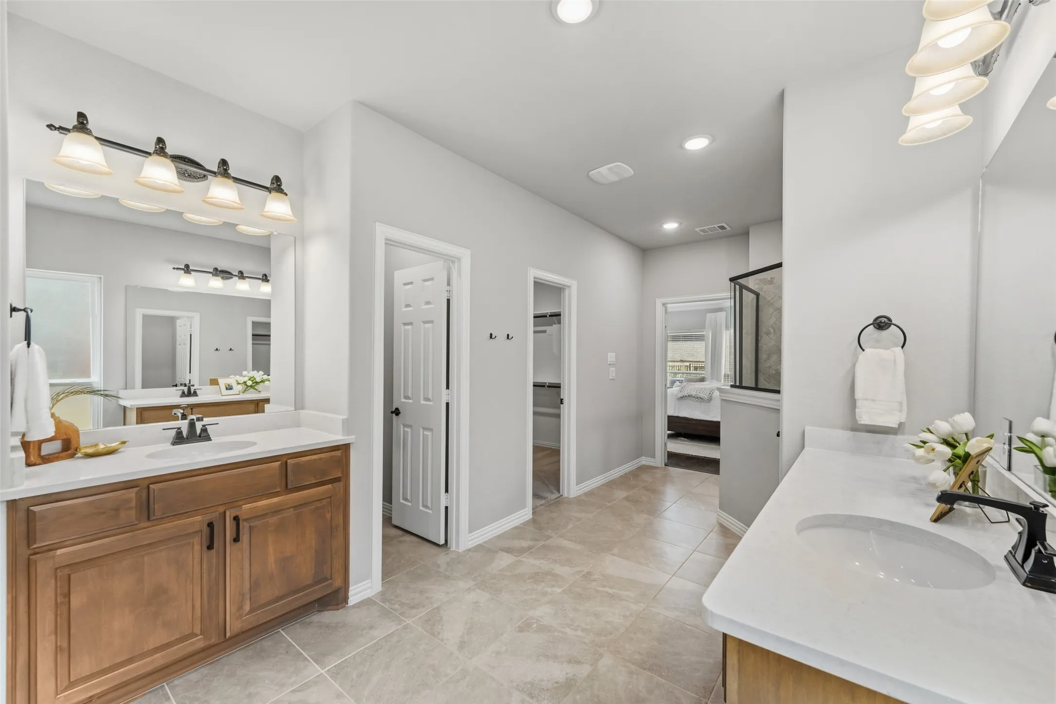 Dual vanities with undermount sinks, wood-finish cabinetry, and overhead lighting