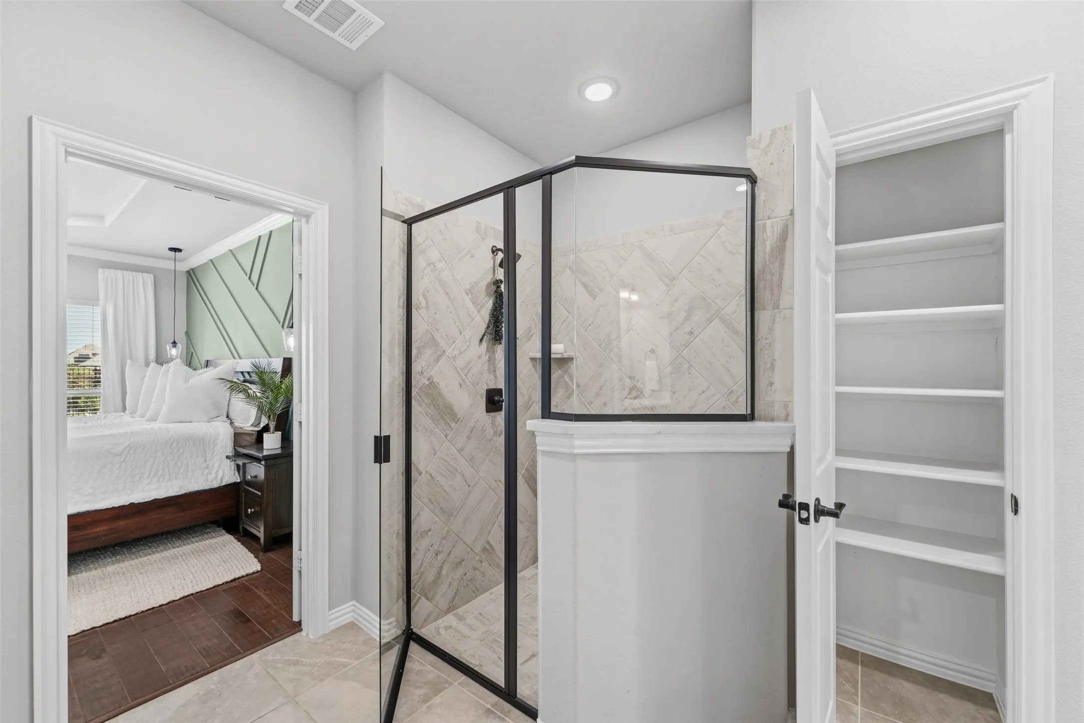 Glass-enclosed shower with tiled walls, built-in shelving, and a dark-finished shower fixture