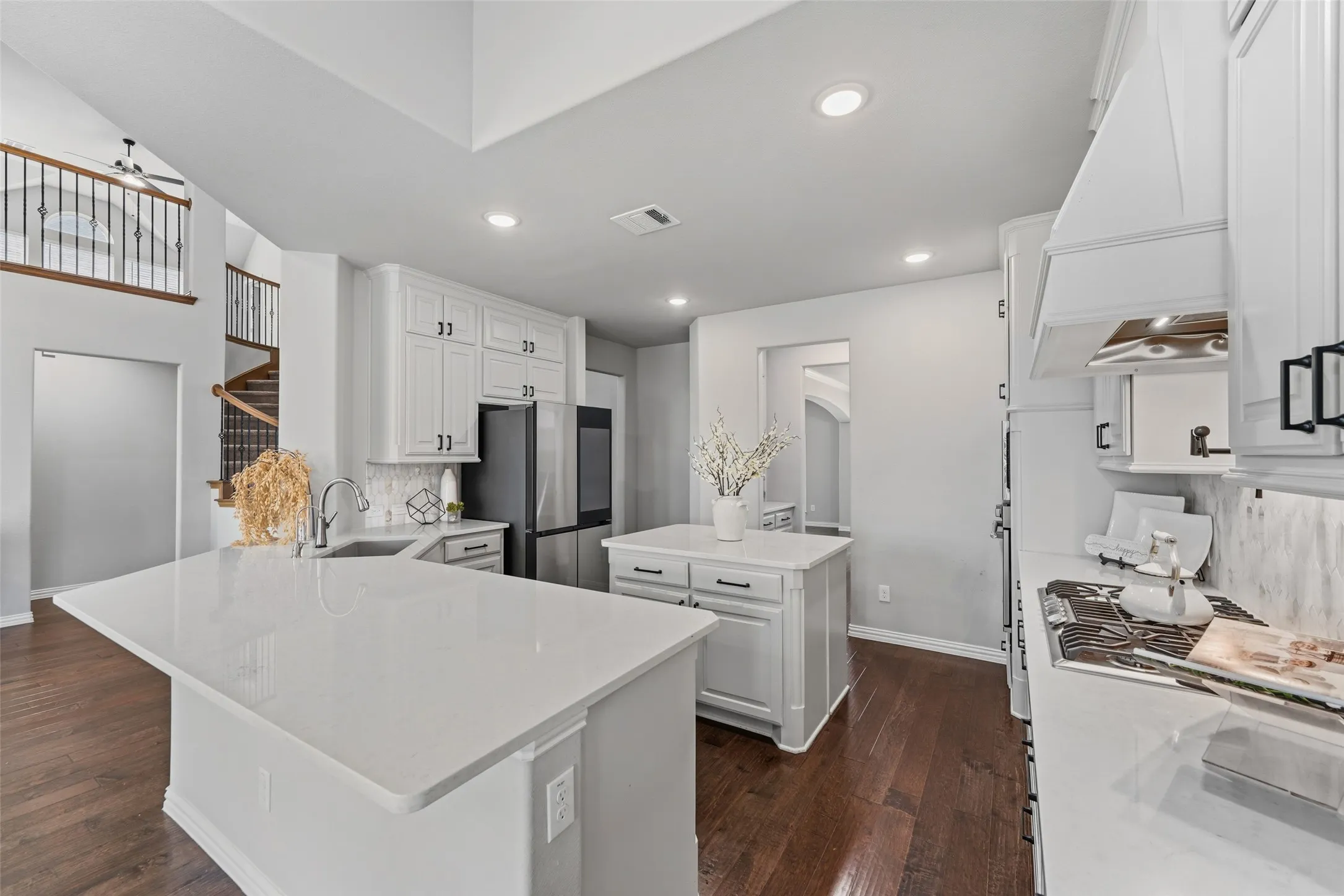 Kitchen featuring a center island, white cabinetry, dark wood-finish flooring, and a stainless steel refrigerator