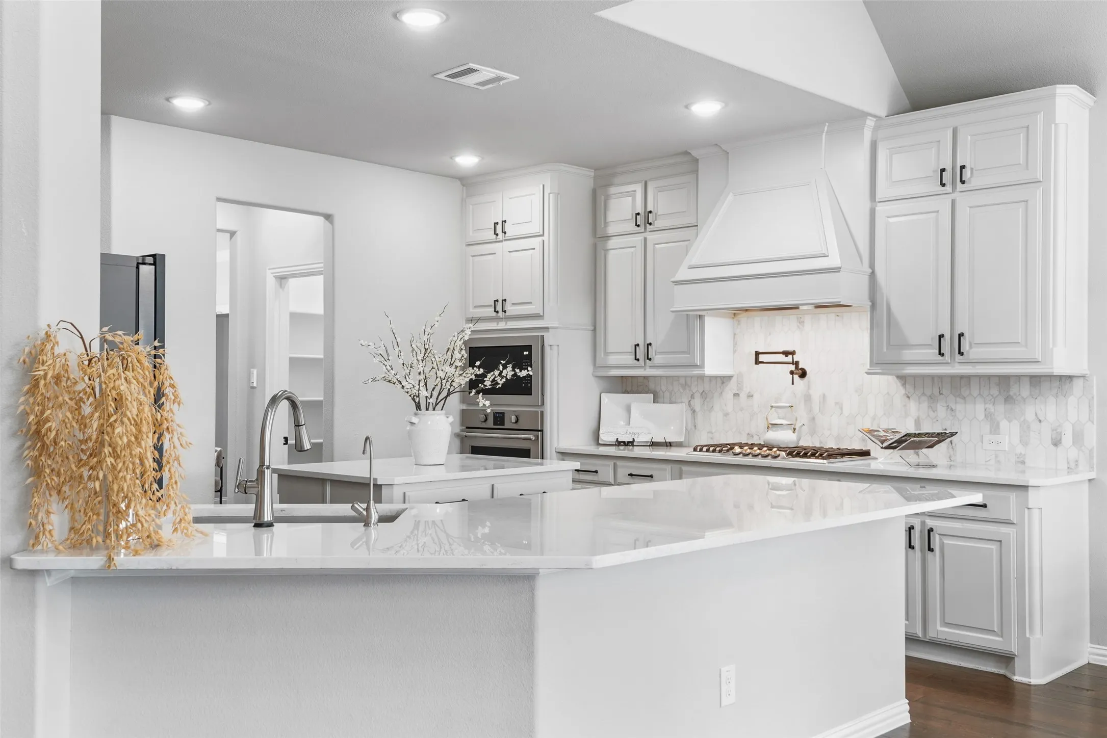 Spacious kitchen featuring white cabinetry, light-toned countertops, and a tile backsplash