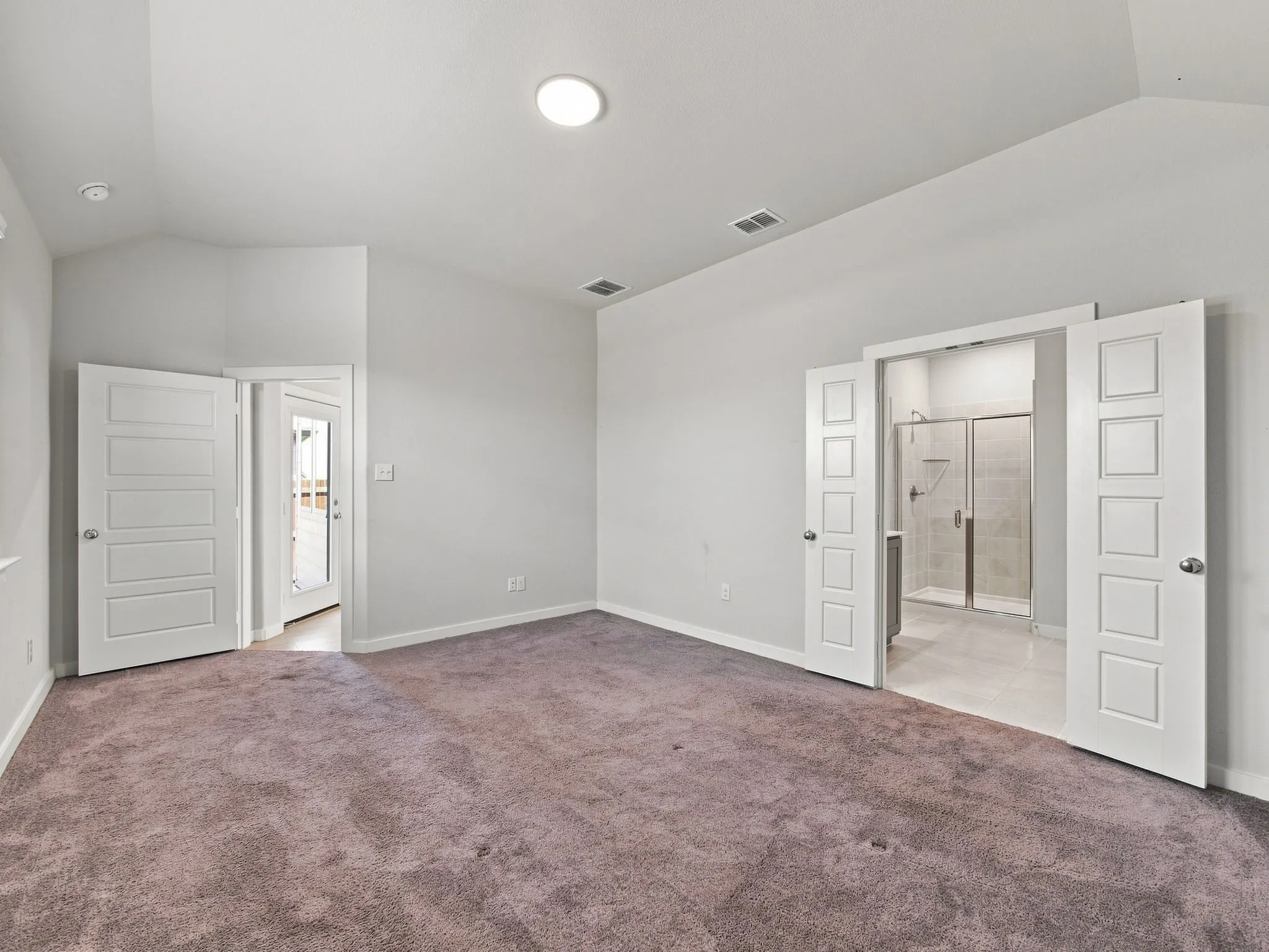 Vaulted ceiling with recessed lighting, carpeted flooring, and white paneled doors