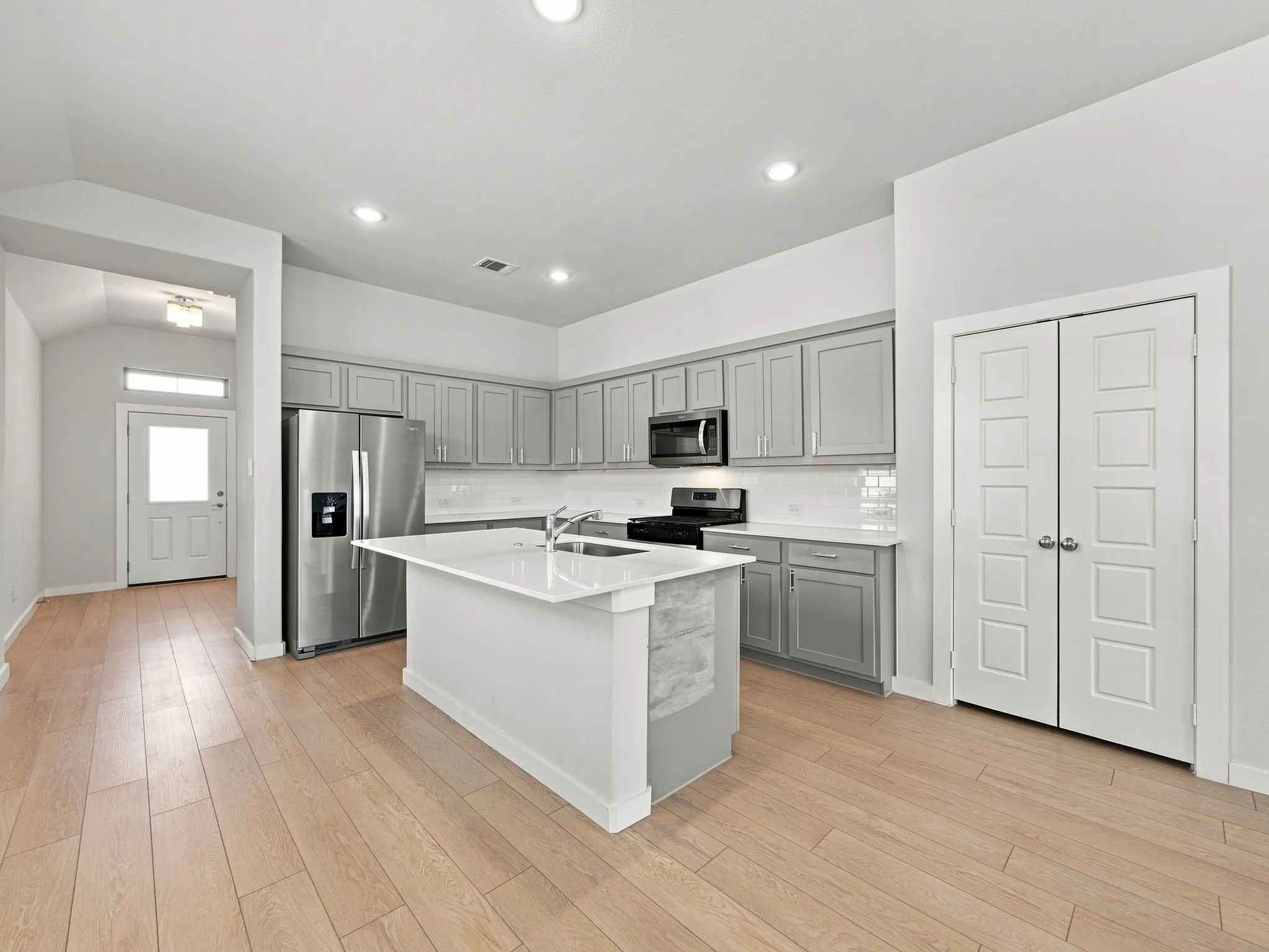 Kitchen featuring light wood-finish flooring, recessed lighting, and a center island with an integrated sink