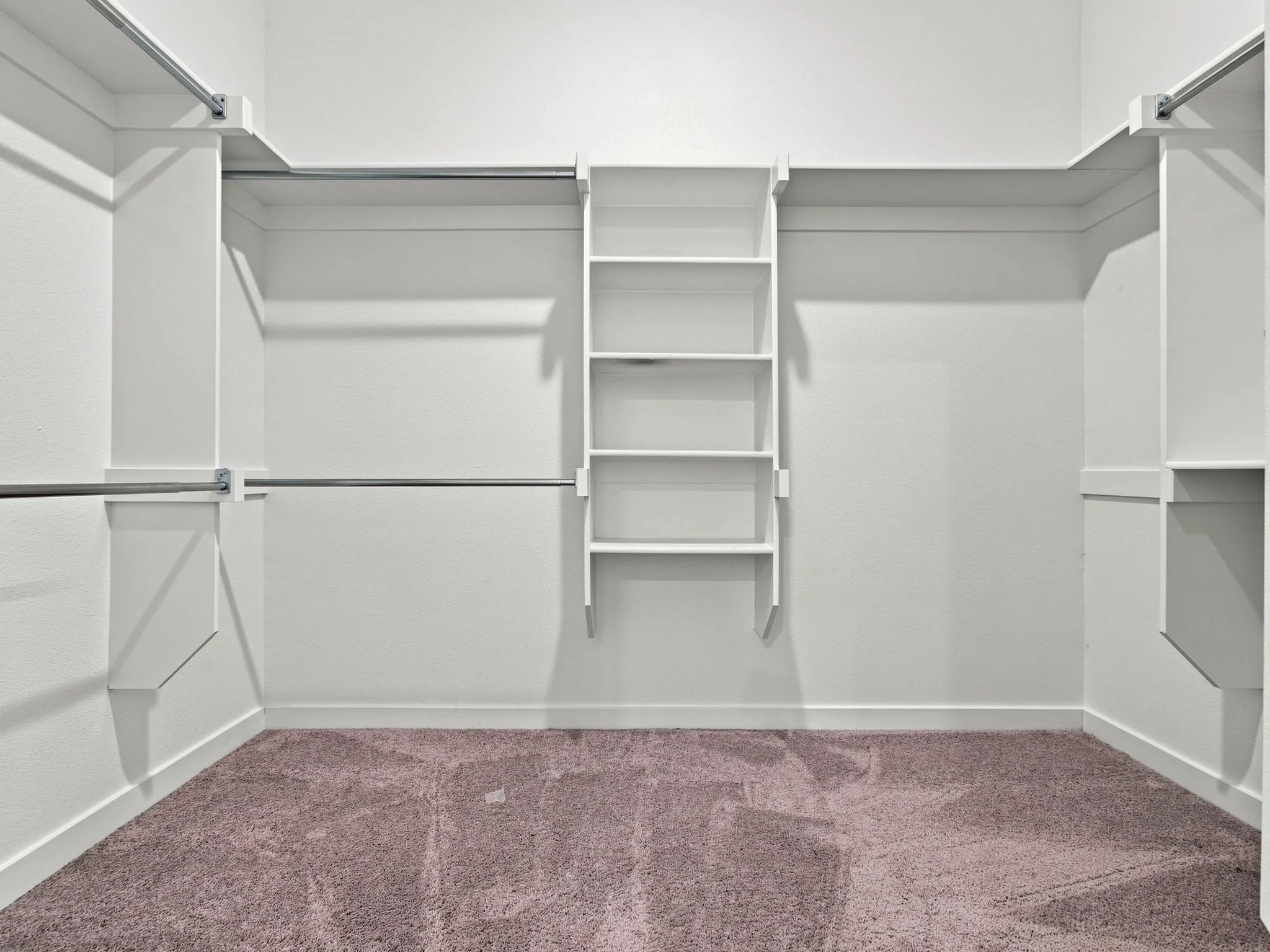 Built-in shelving, multiple hanging rods, and neutral carpet flooring