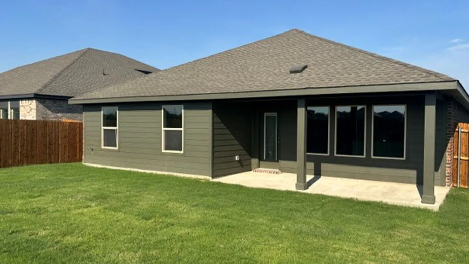 Expansive rear yard featuring green lawn, a covered patio, and a privacy fence