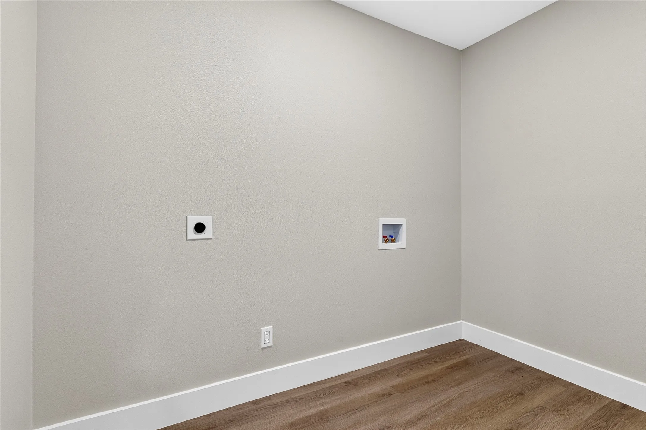 Wood-finish flooring with white trim and a neutral wall color