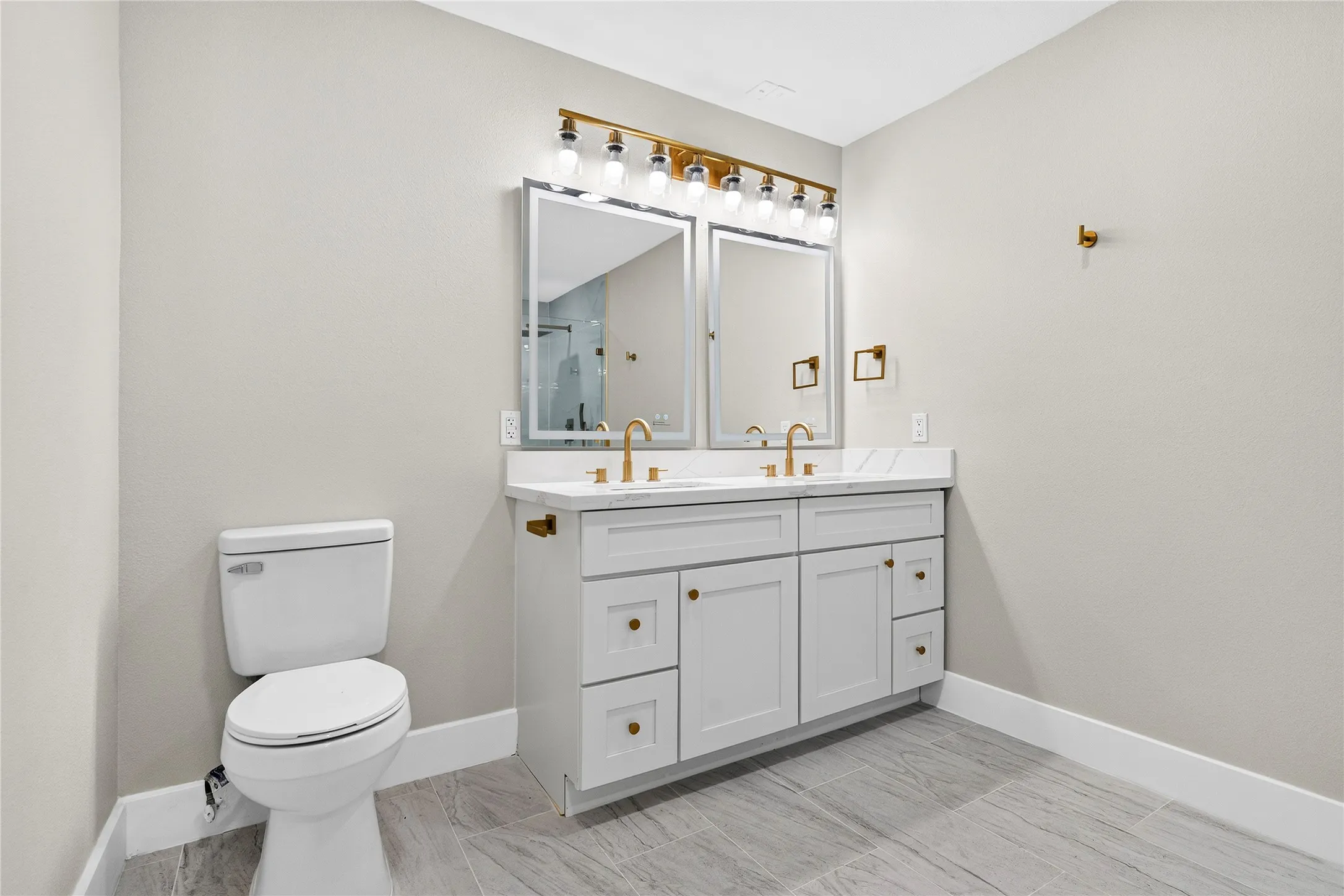 Dual vanity with a white countertop and gold-finish fixtures