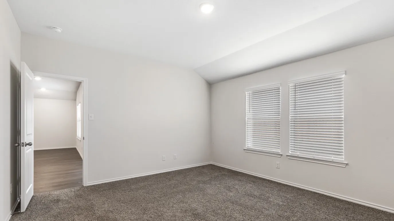 Vaulted ceiling, two windows with blinds, gray carpet, white walls, and a white interior door