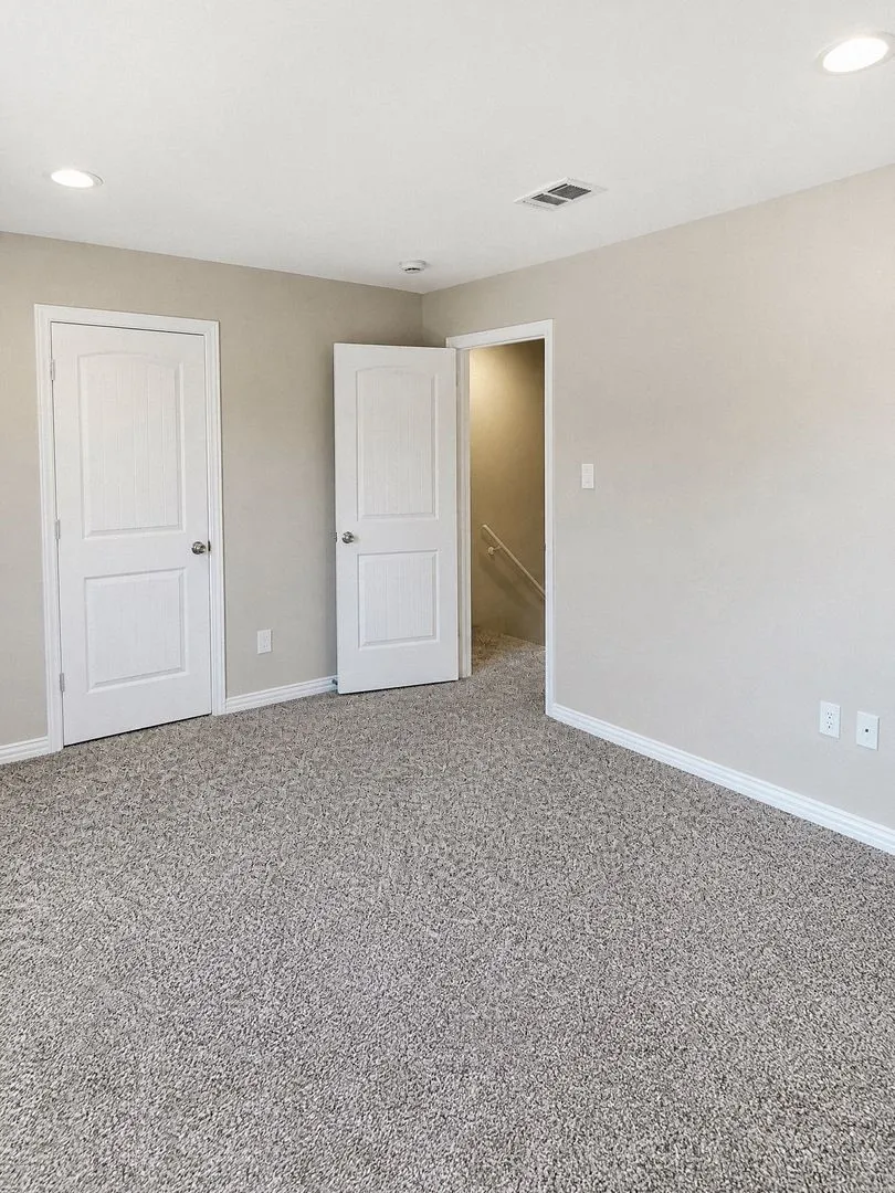 Recessed ceiling lighting, light gray wall paint, and gray textured carpet